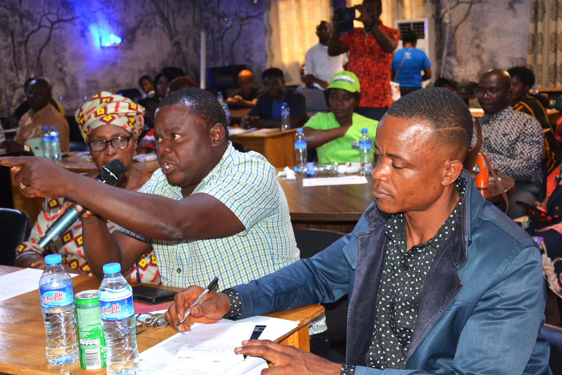 A group of people in a meeting, with one man speaking and others listening attentively.