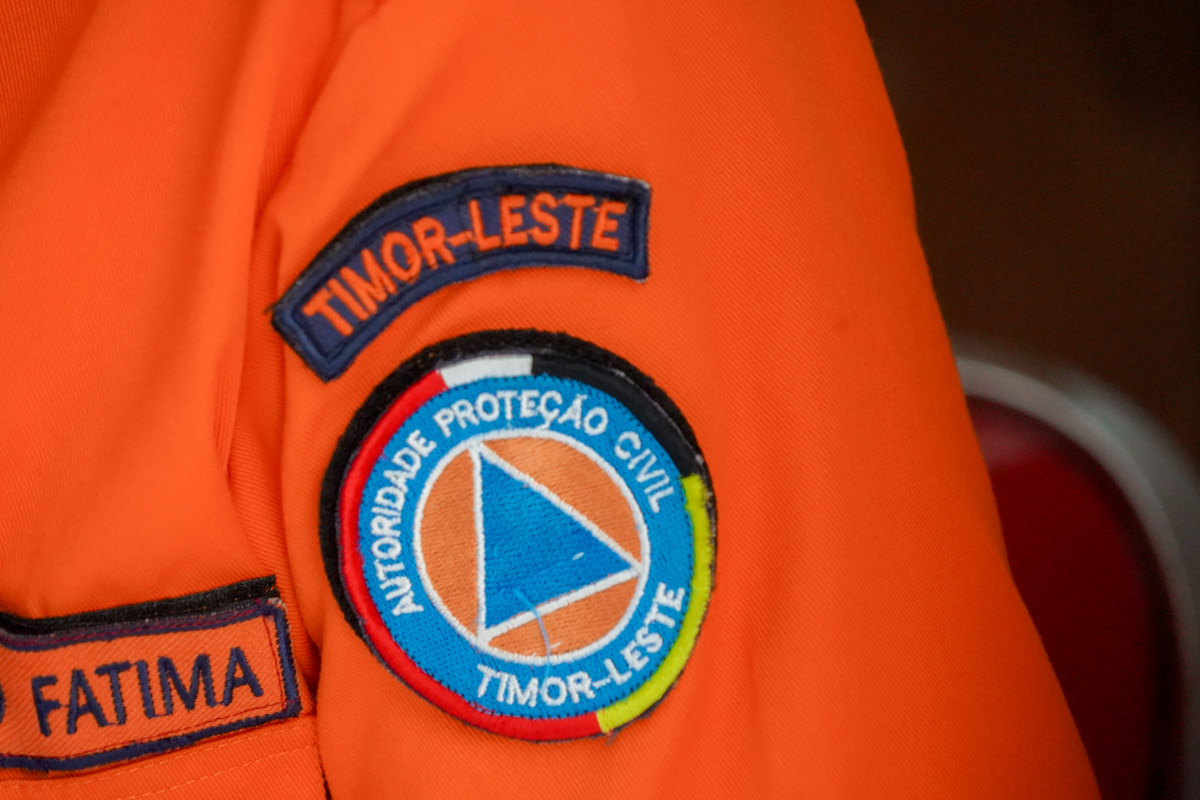 Close-up of orange uniform with Timor-Leste civil protection patches.