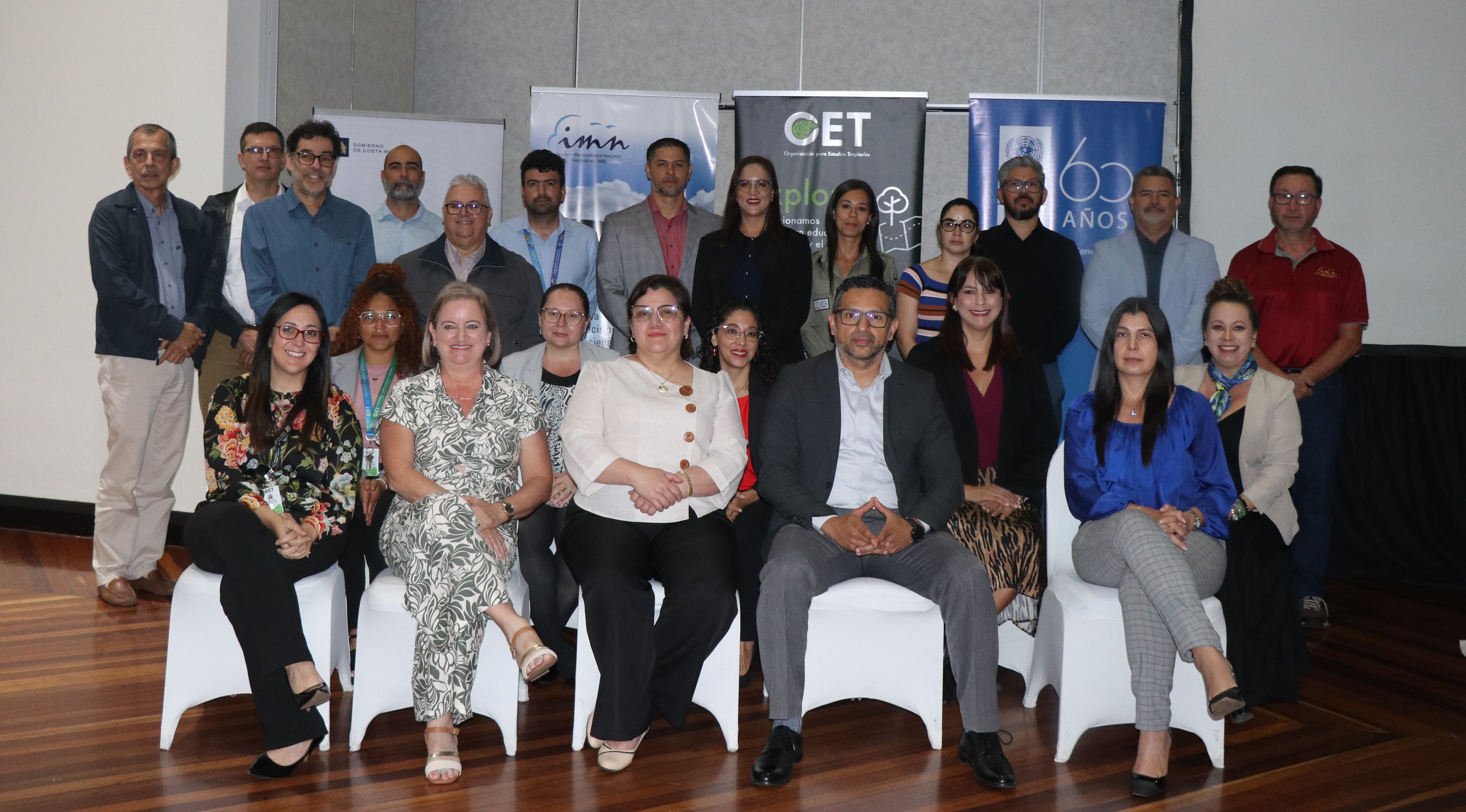Group photo of professionals posing together, smiling, in a conference setting.