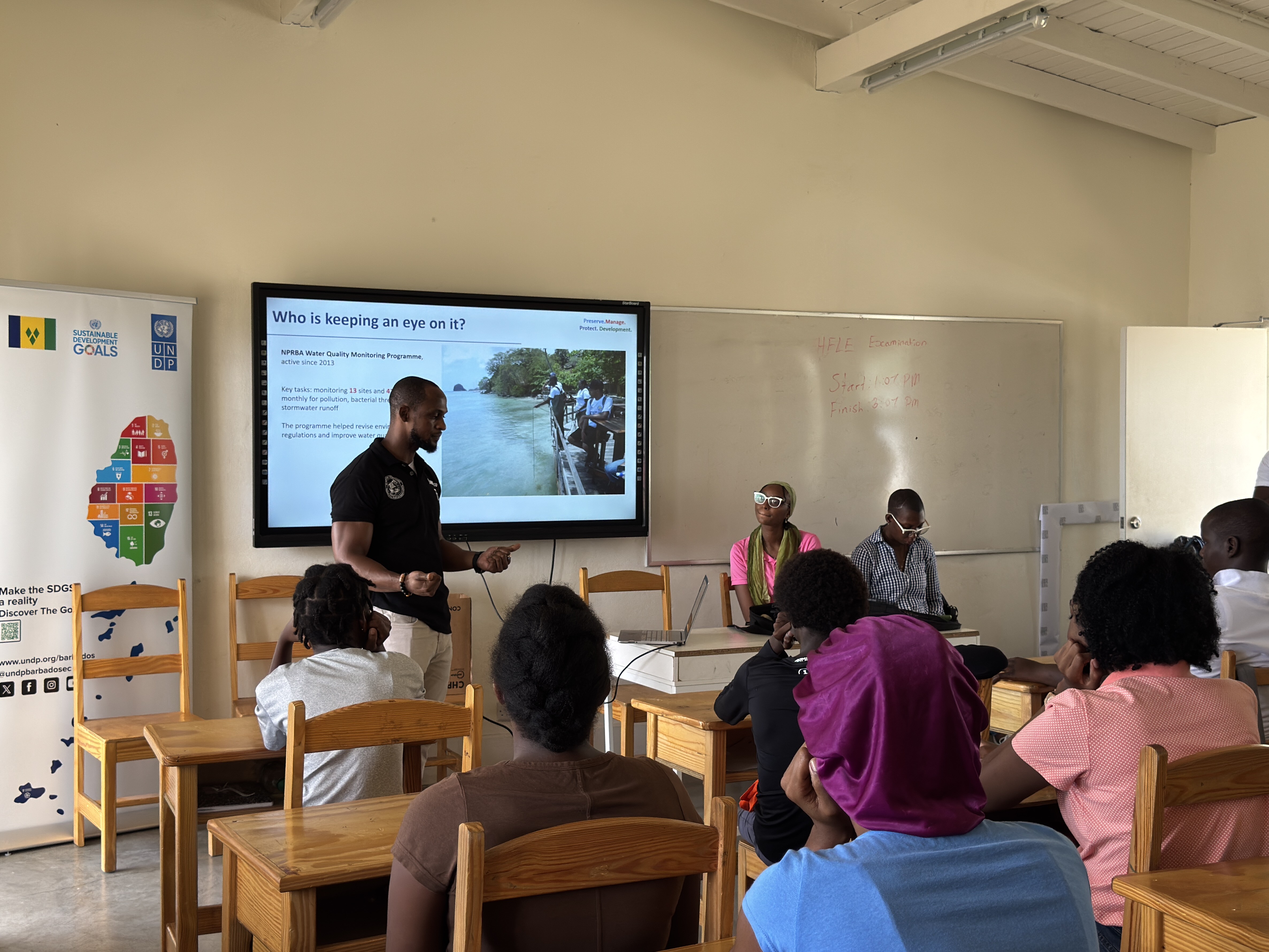 Speaker gives talk to attentive audience in a classroom; slide features a forest scene.