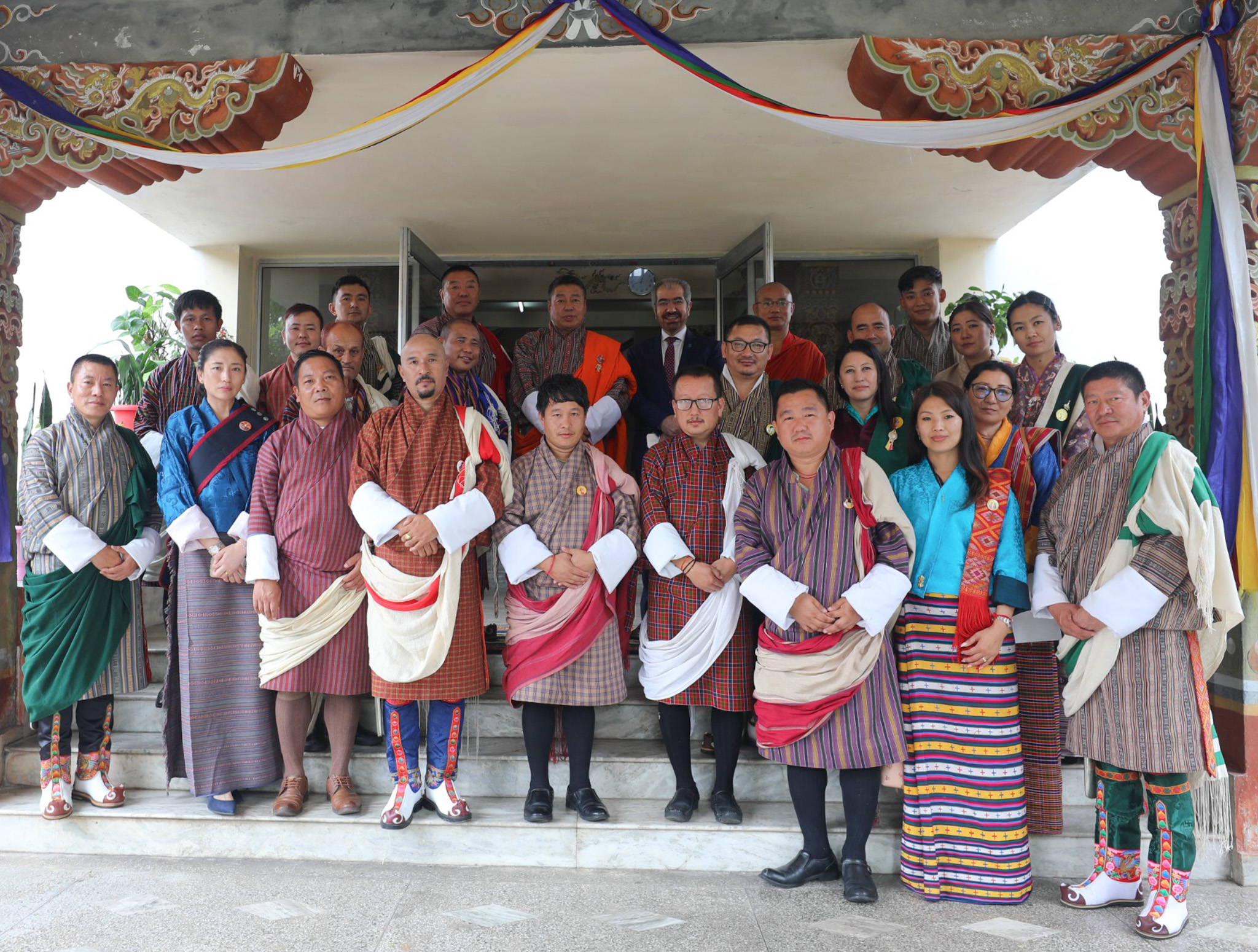 Group of people in traditional attire posing together in a ceremonial setting.