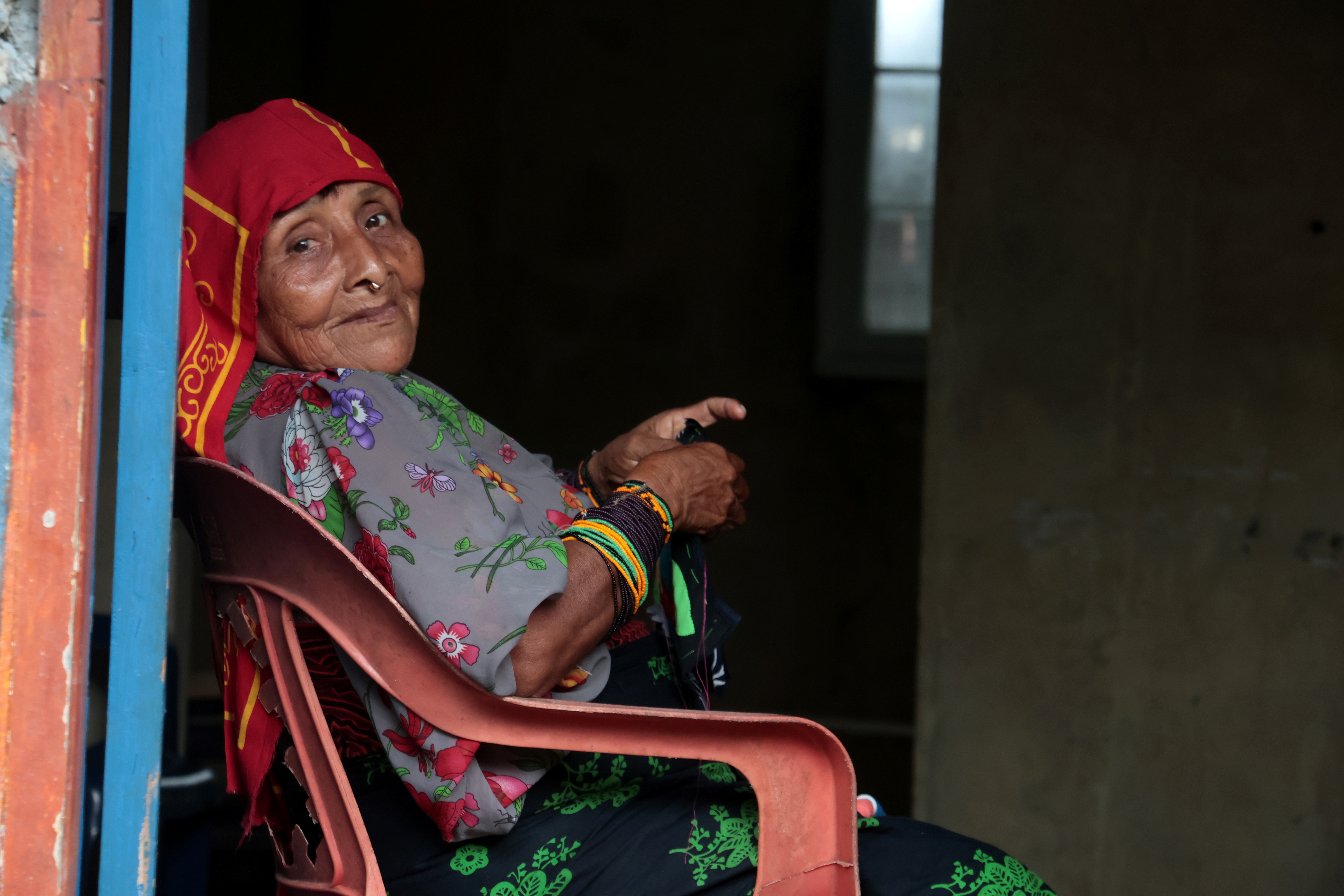 Una mujer indìgena con vestido colorido está sentada sonriendo hacia el frente