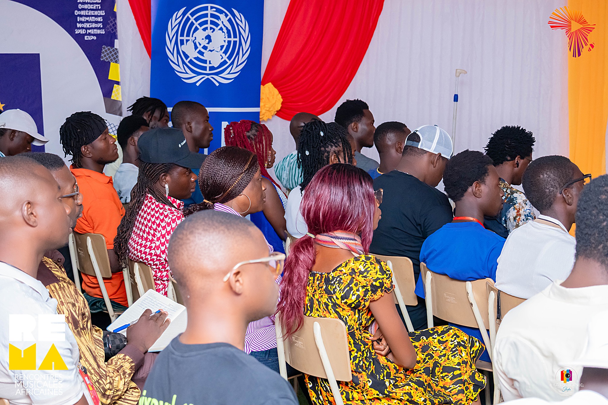 Diverse audience seated at a conference with a United Nations flag in the background.