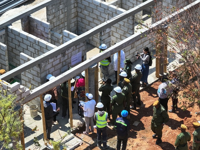 Group of people in hard hats stand near a building