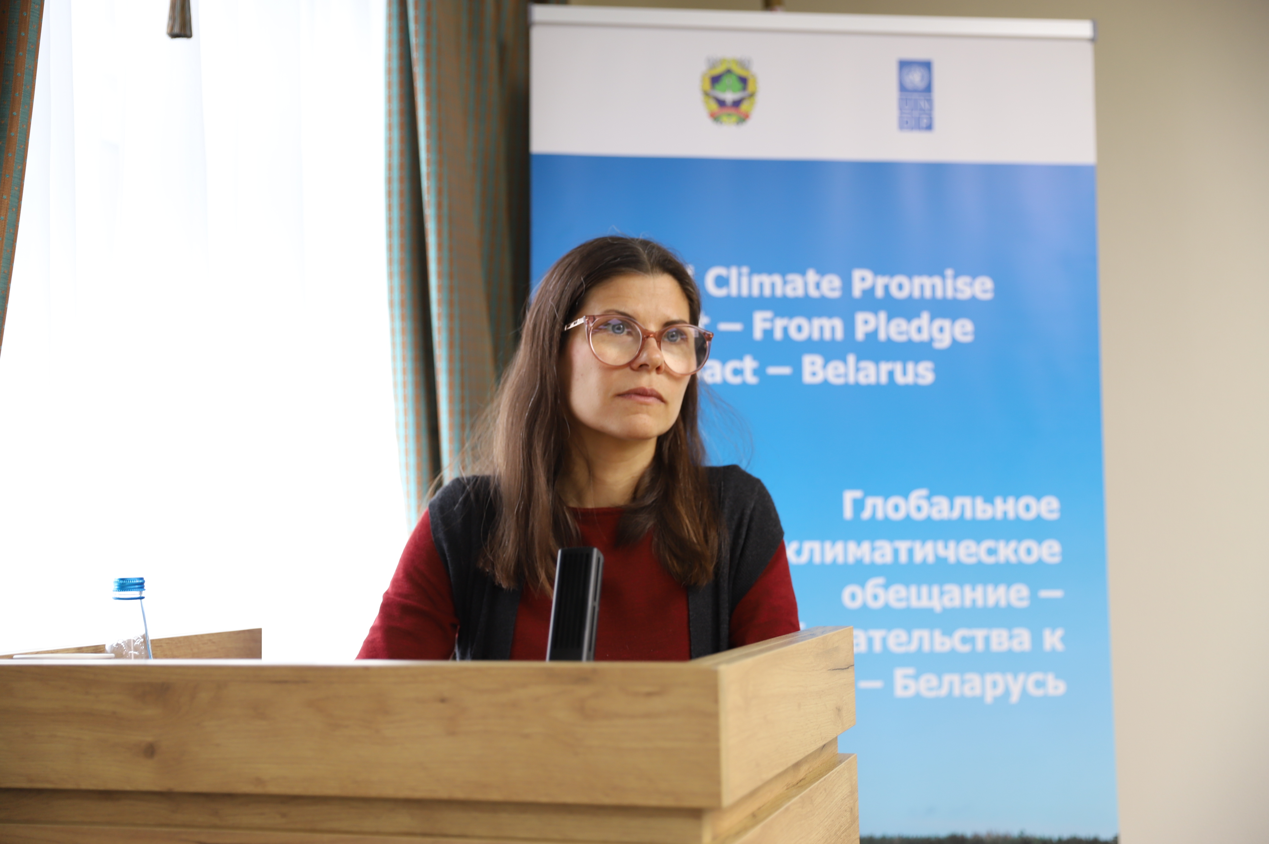 Speaker at a wooden podium with a blue climate banner in the background.