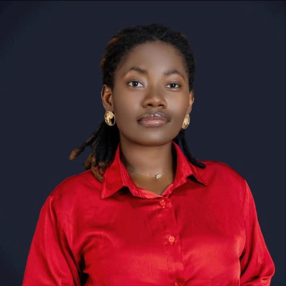 Person in a red collared shirt against a dark backdrop, wearing gold earrings.