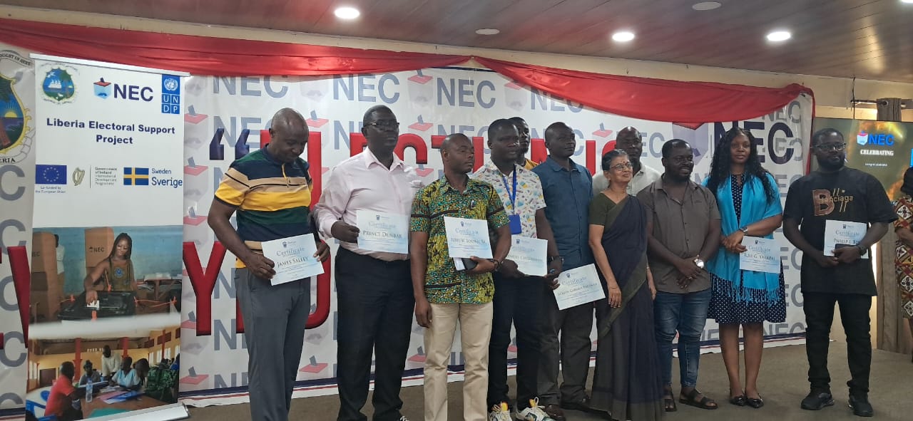 Group of people on stage at NEOC event, holding certificates.