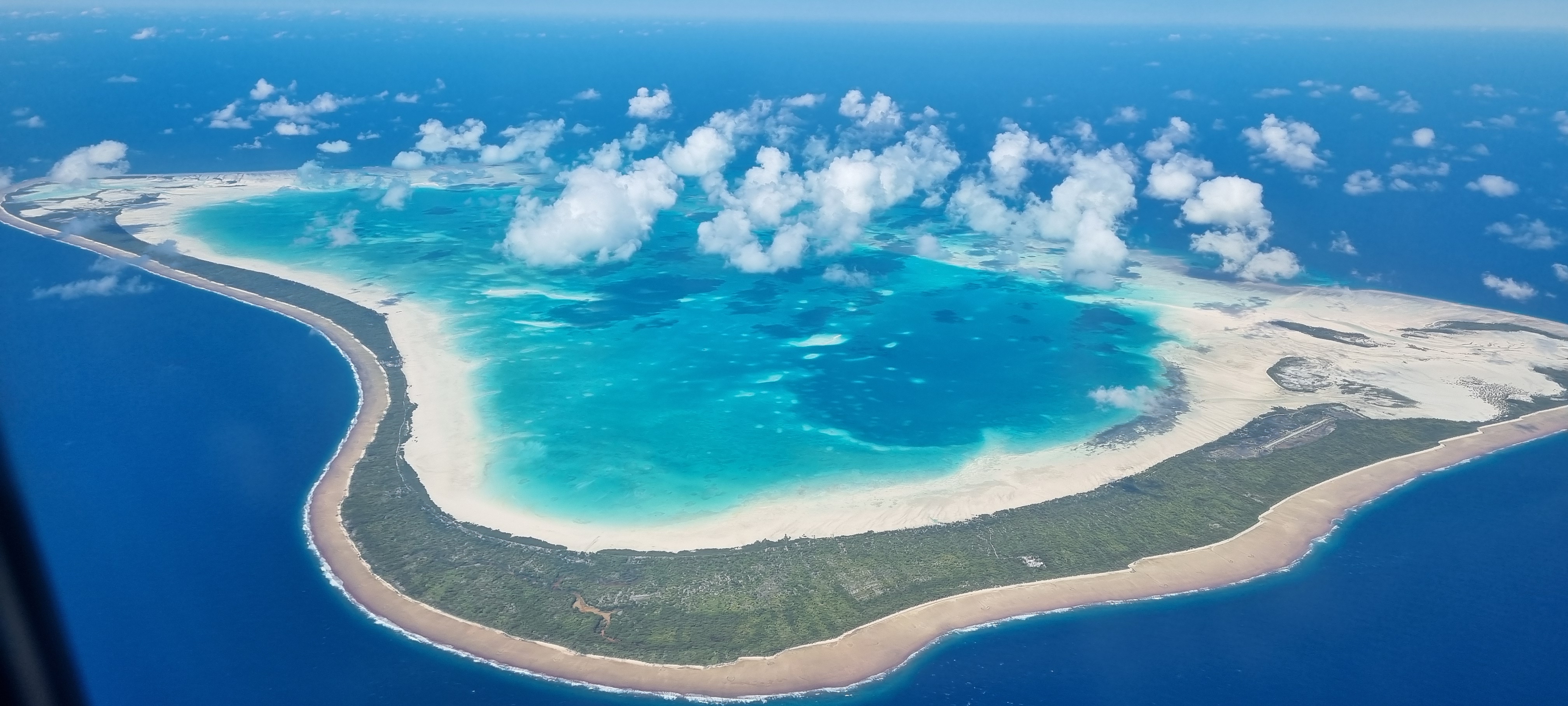 Aerial view of a tropical island with a turquoise lagoon and white sandy beaches.
