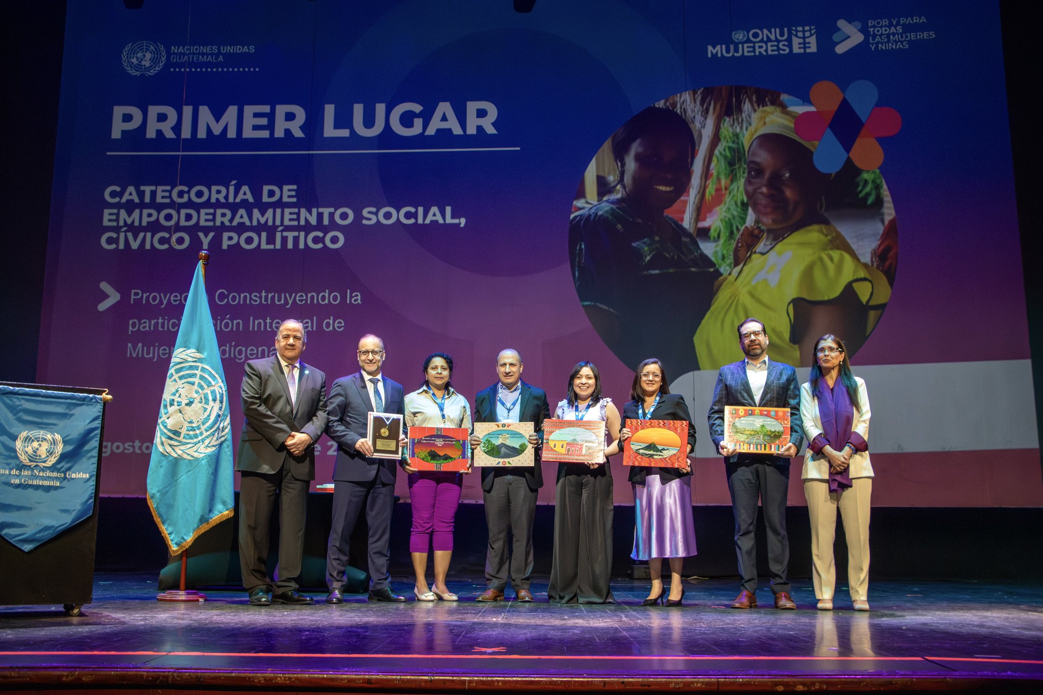 Group of awardees on stage holding certificates during a first-place awards ceremony.