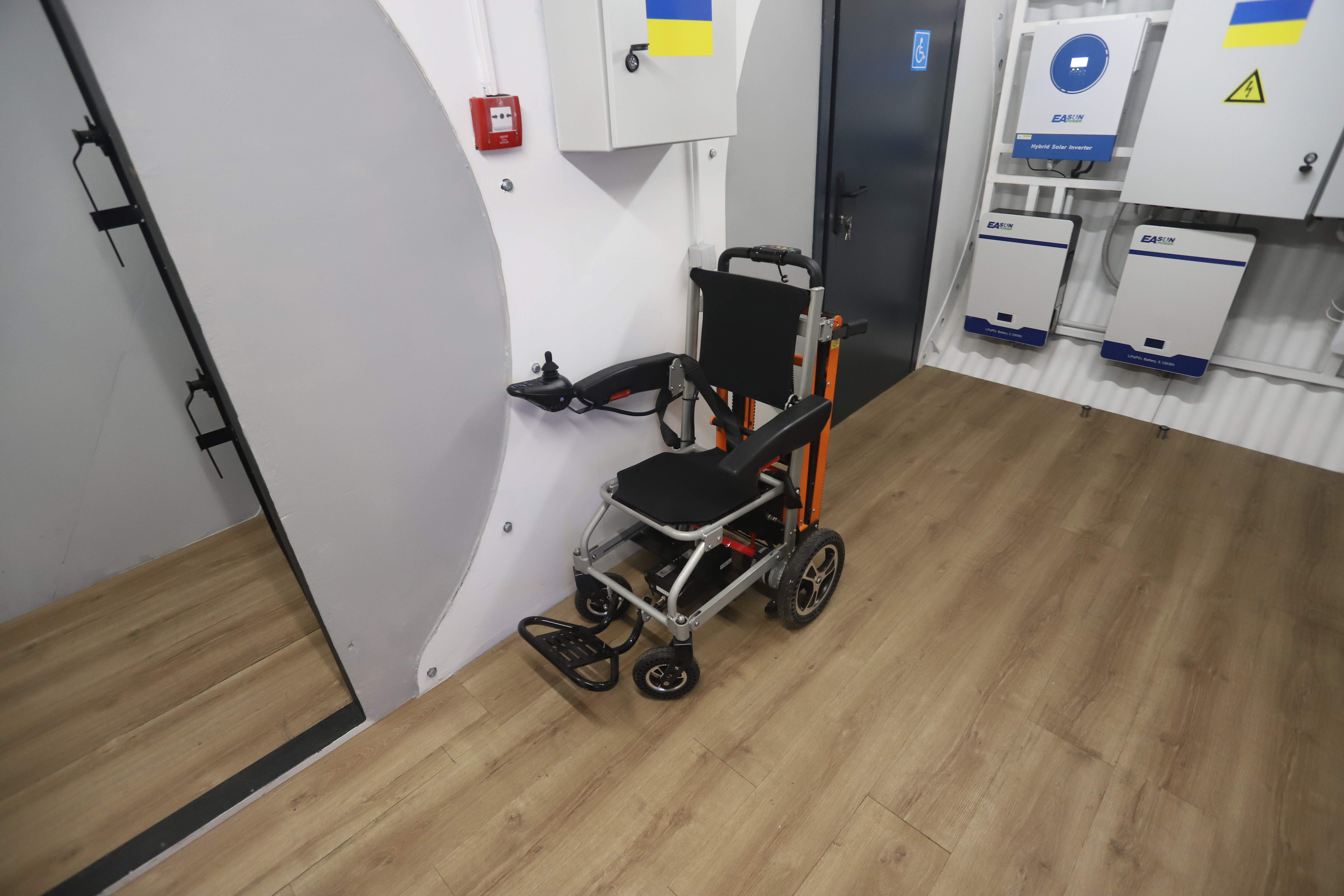 Wheelchair in a hospital hallway with a wooden floor and medical cabinets.