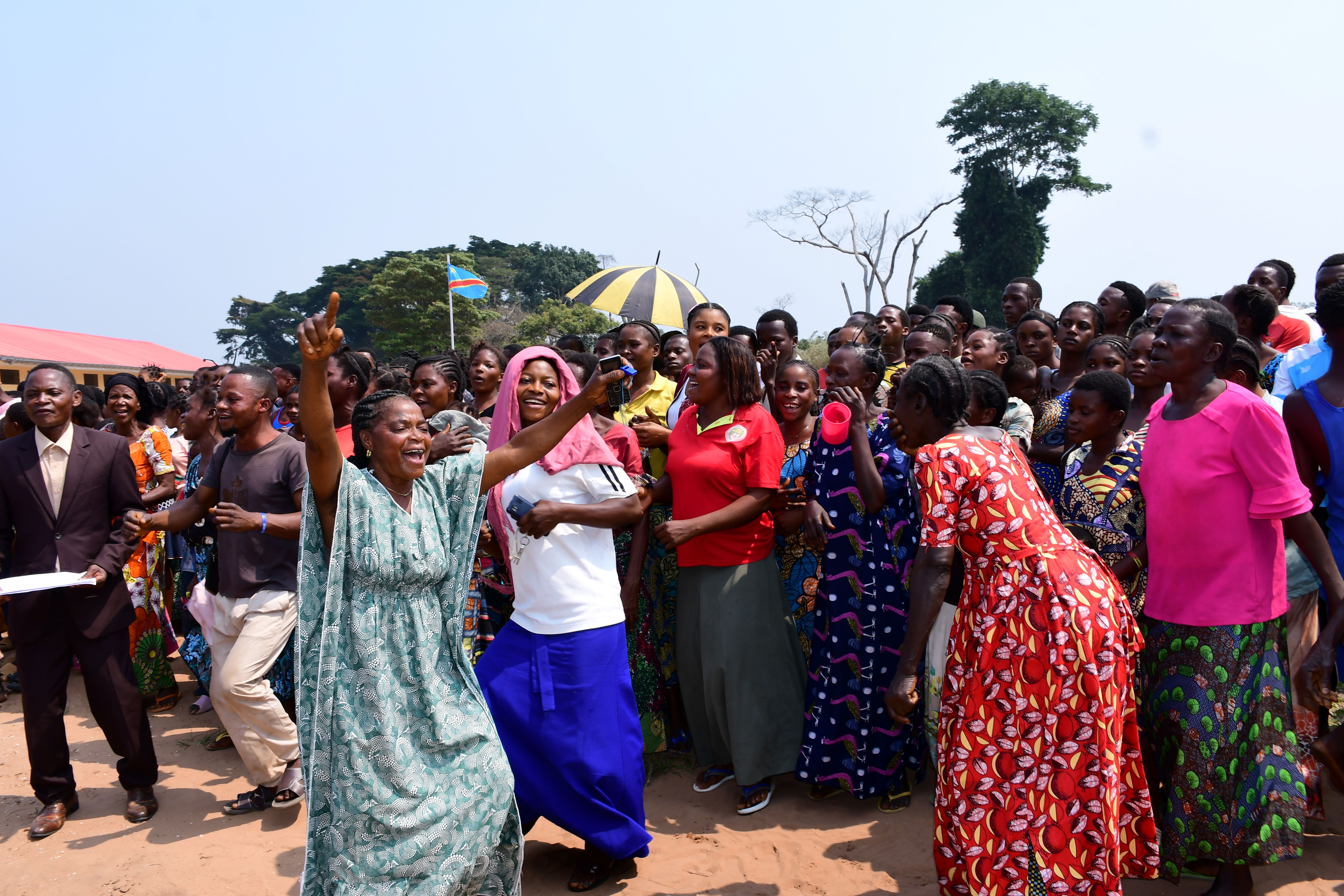 Photograph of a large crowd wearing colorful outfits gathered outdoors on a sunny day.