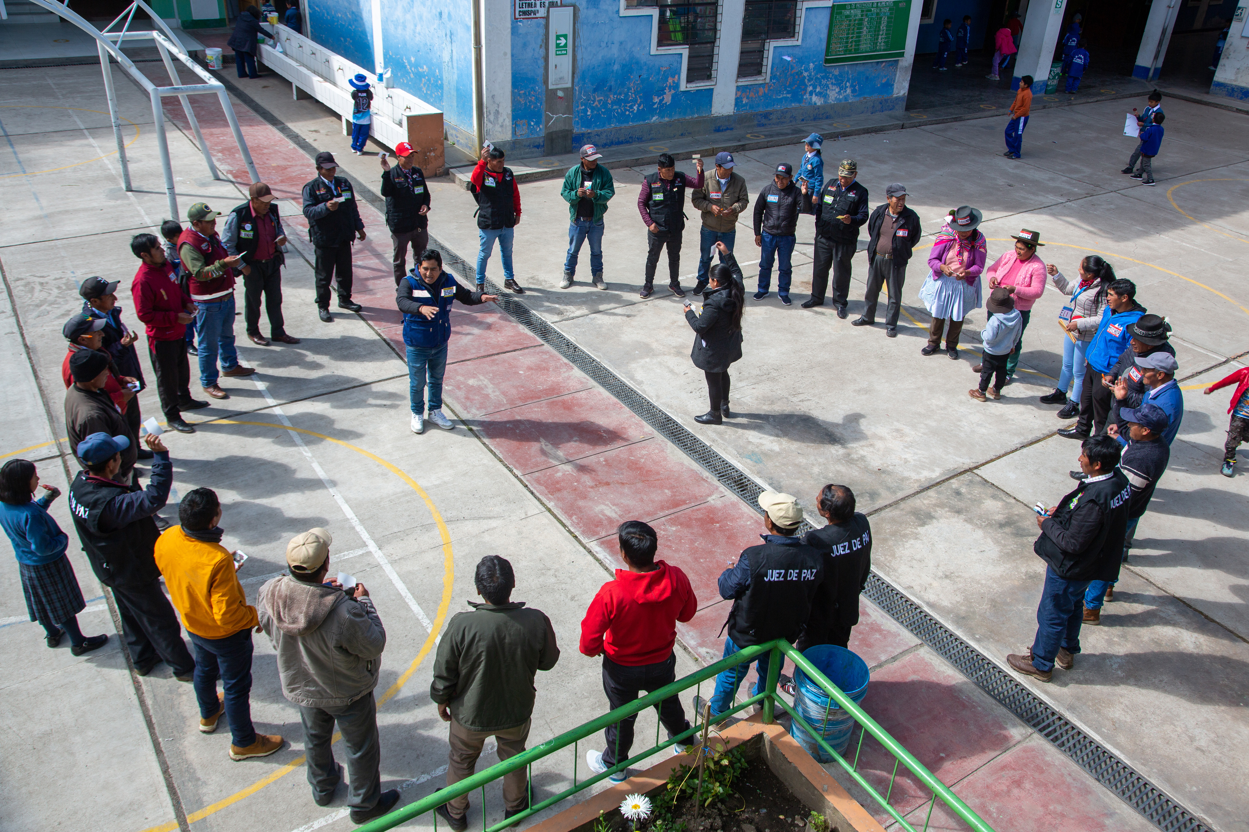 Photo: Diverse group standing in a circle in a schoolyard courtyard.