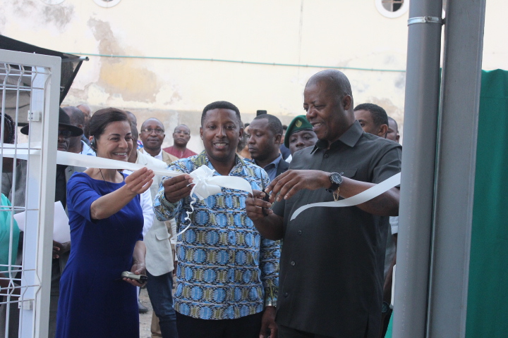 Group of people outdoors raising cups in a toast near a doorway.