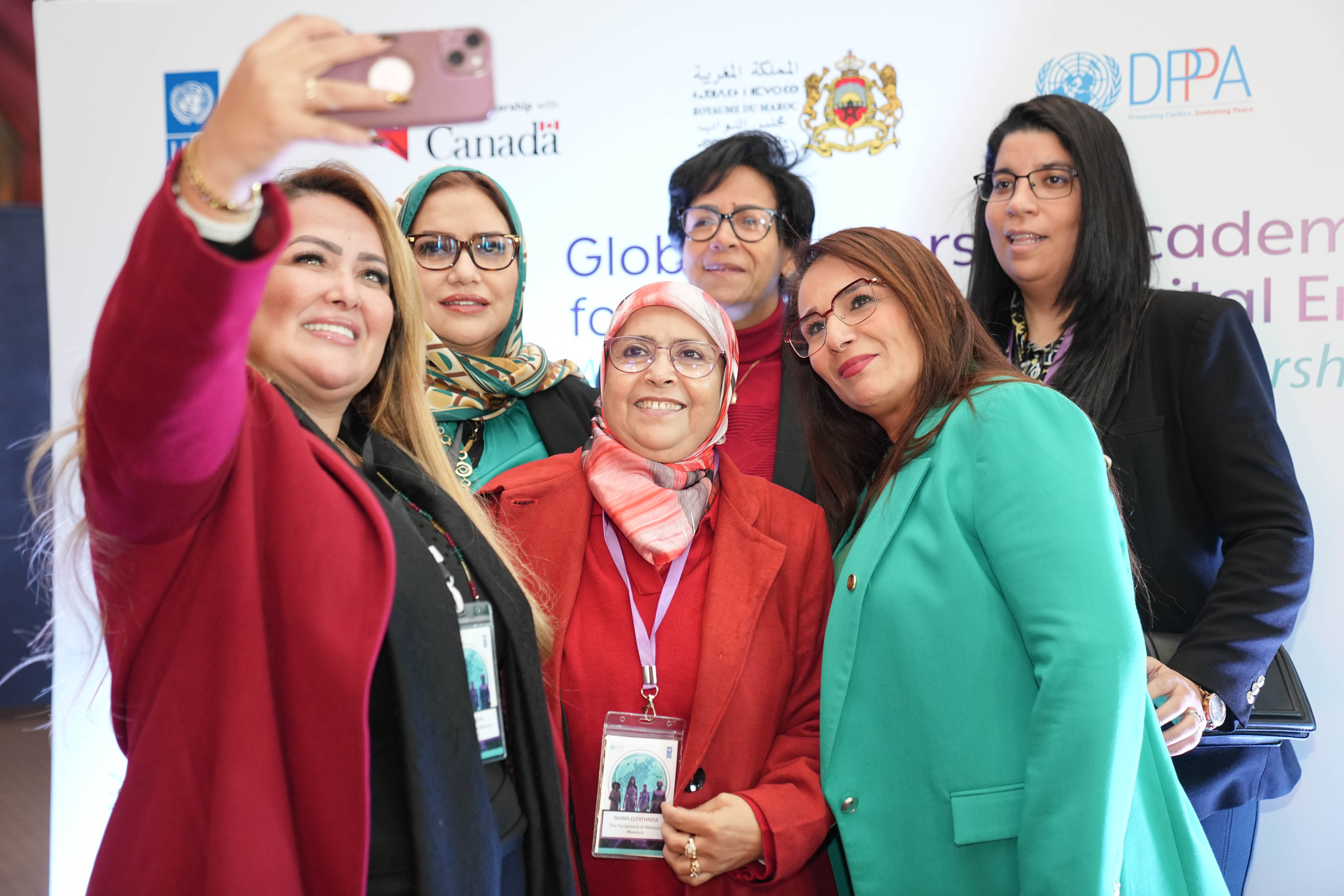 Group of people posing for a photo at an event, banners visible in the background.