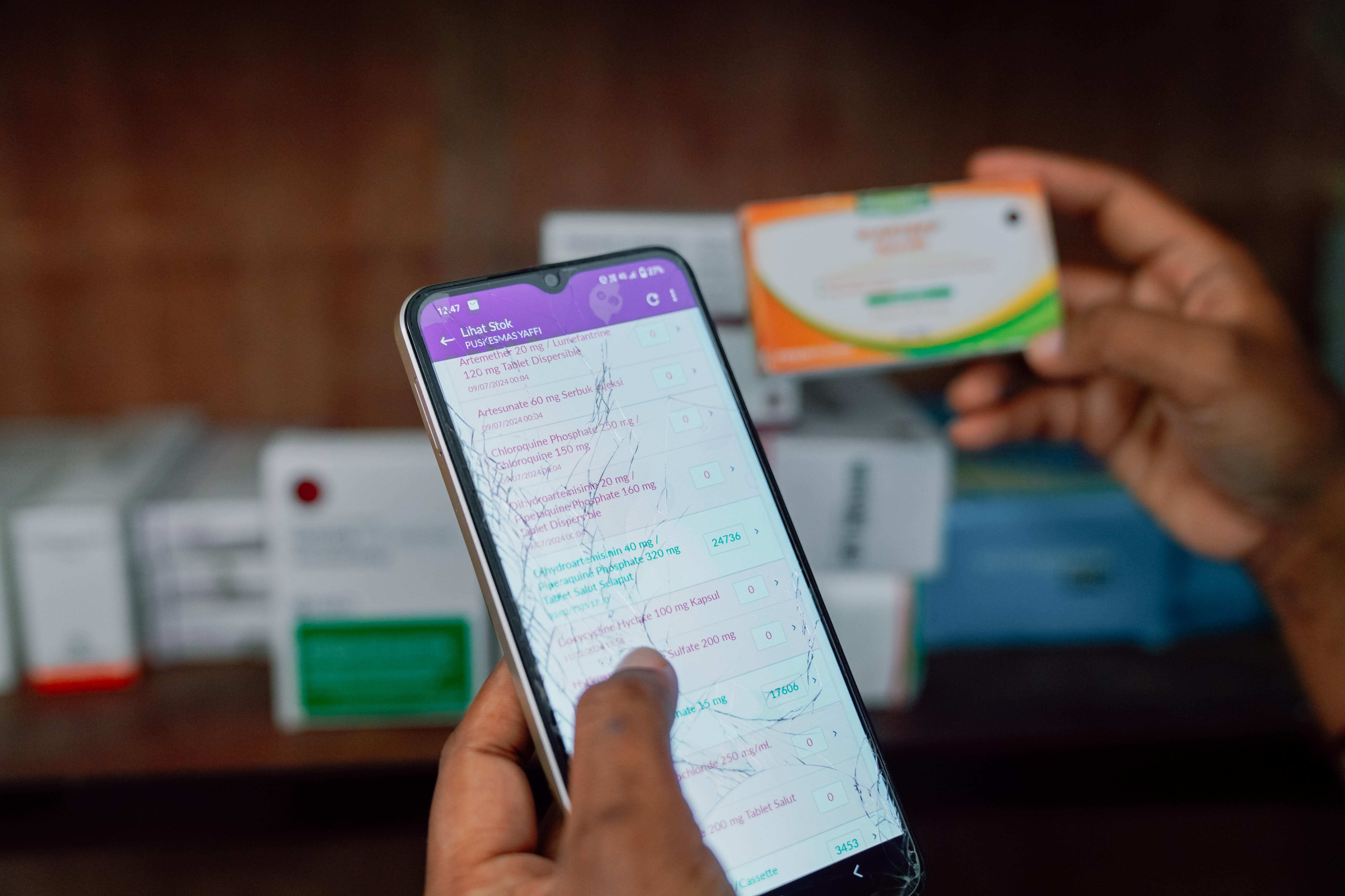 Photo: Hands hold a smartphone displaying a list; another hand holds a payment card in a store.