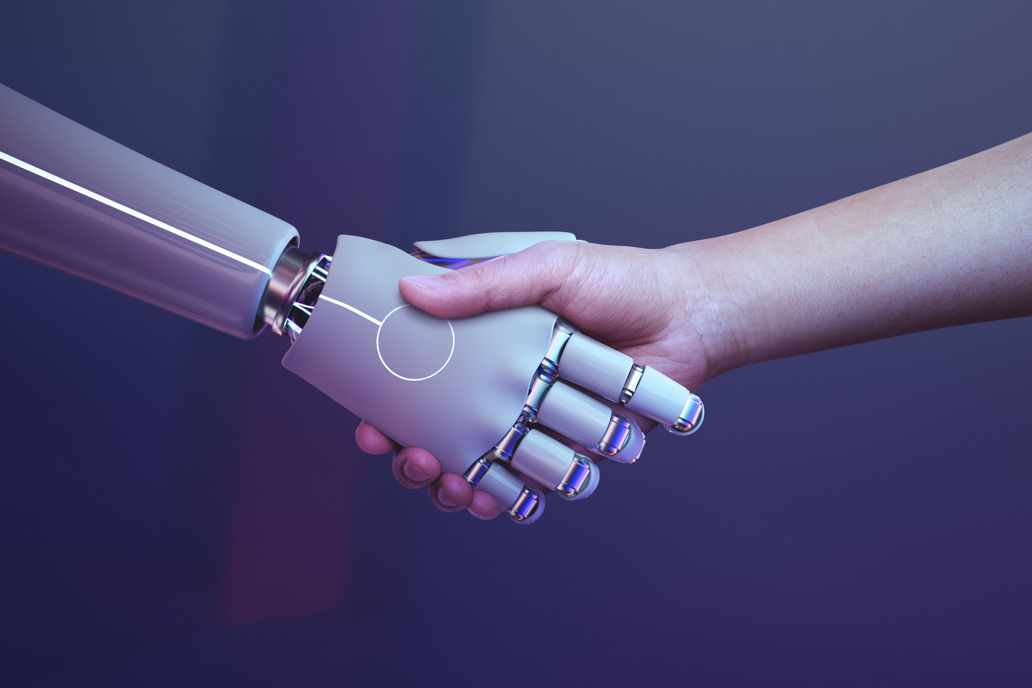 Photo: handshake between a human hand and a robotic prosthetic hand under purple lighting.