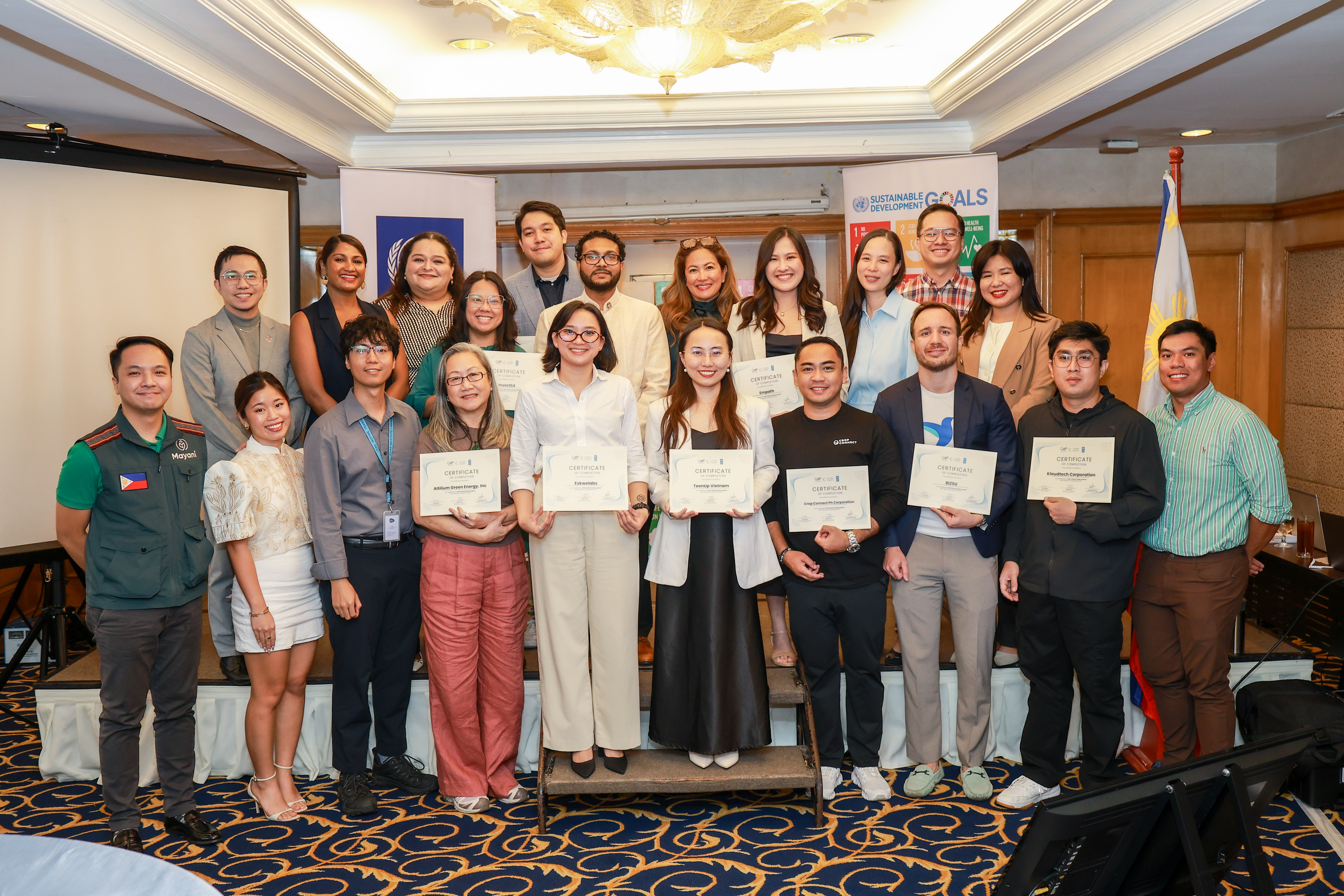 Group of adults standing in rows, holding certificates in a conference room.