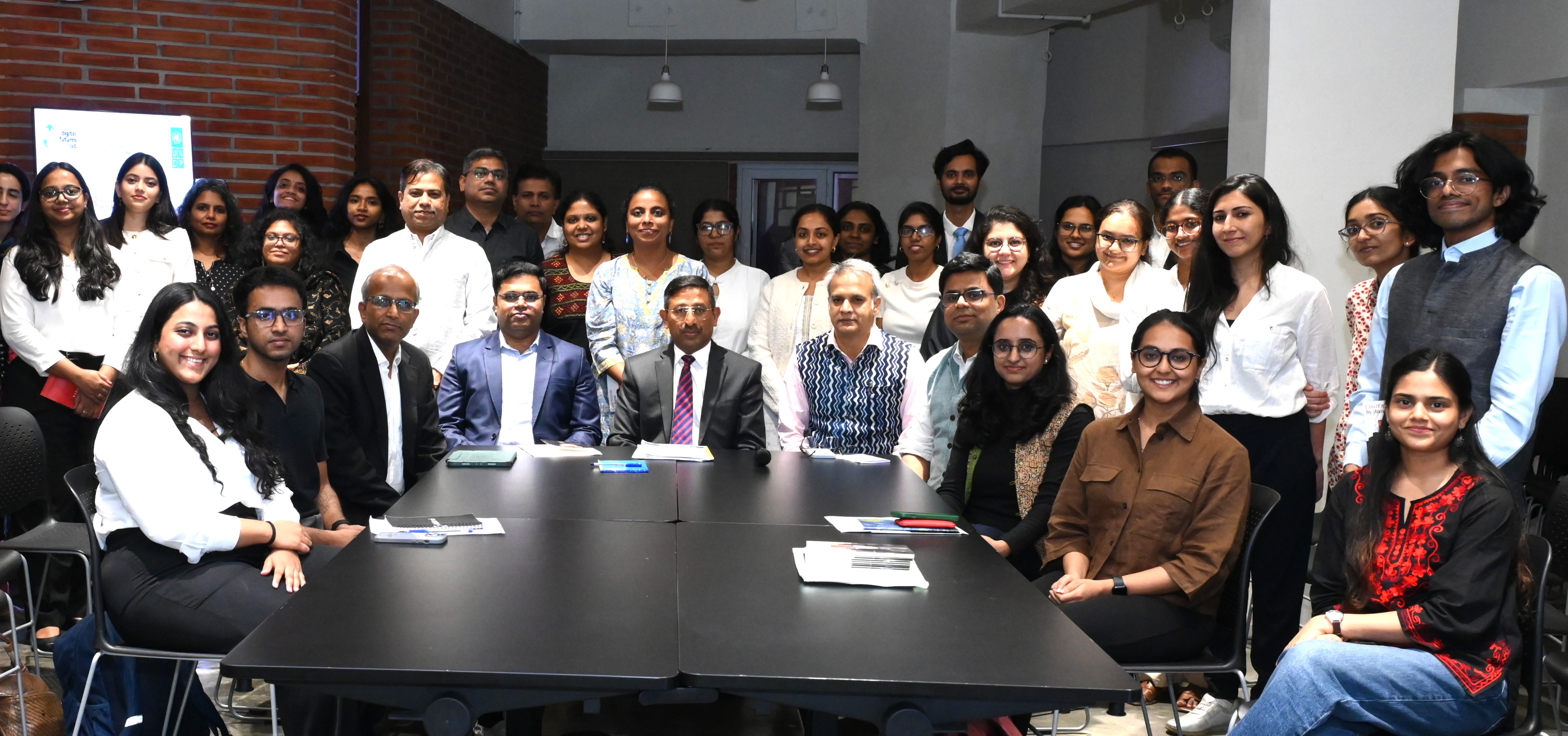 Photo: diverse group of professionals posing around a long conference table in a modern office.