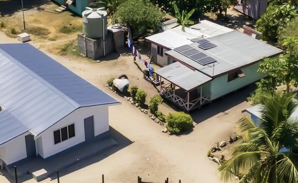 Aerial view of a small tropical compound with two buildings and palm trees.