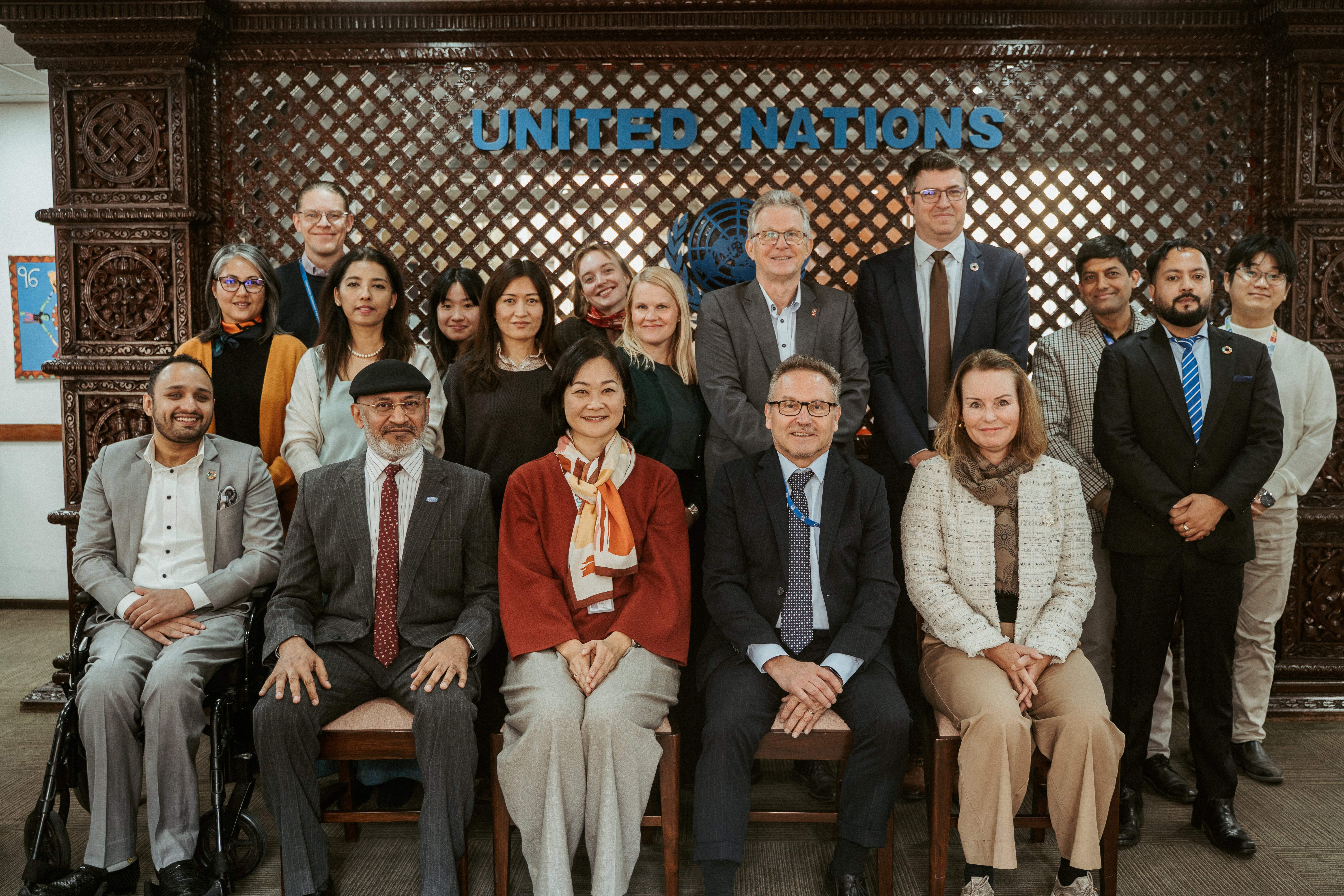 Group of professionals posing for a formal photo in a conference room, United Nations sign.