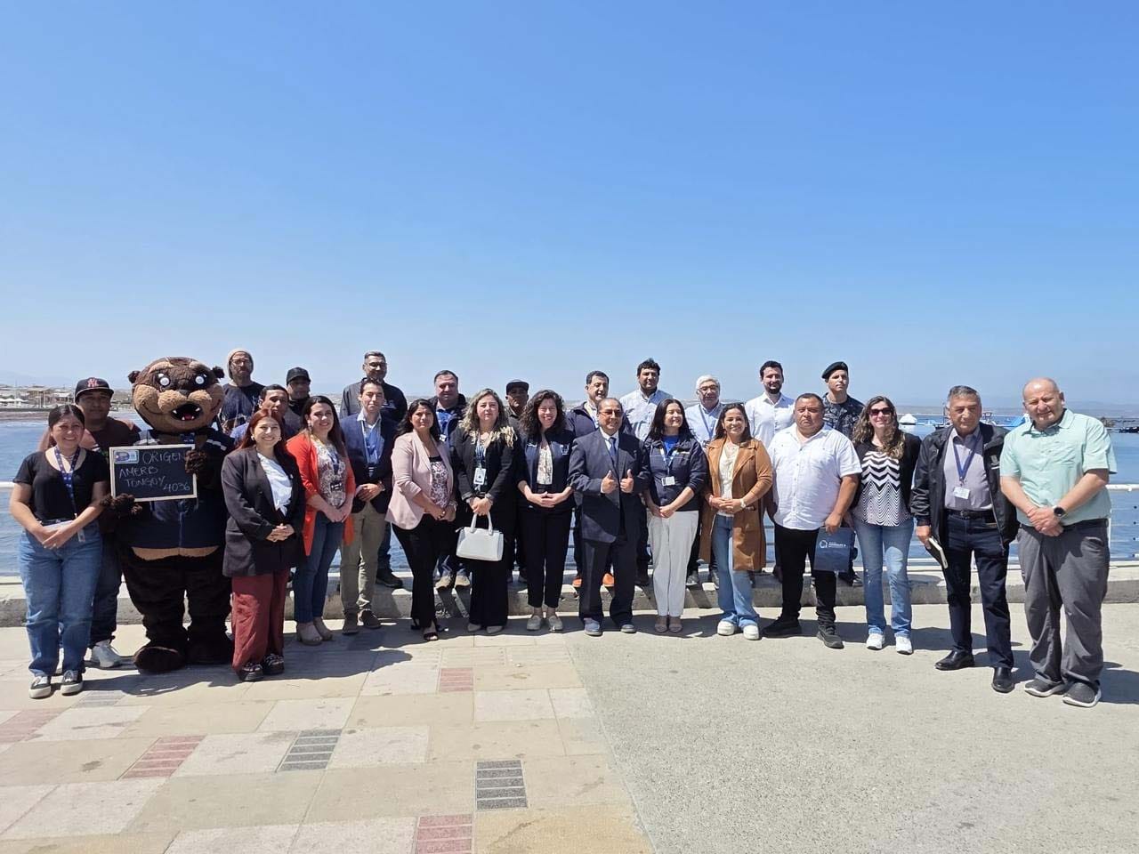 Diverse group smiling for a photo outdoors on a sunny day by the water.