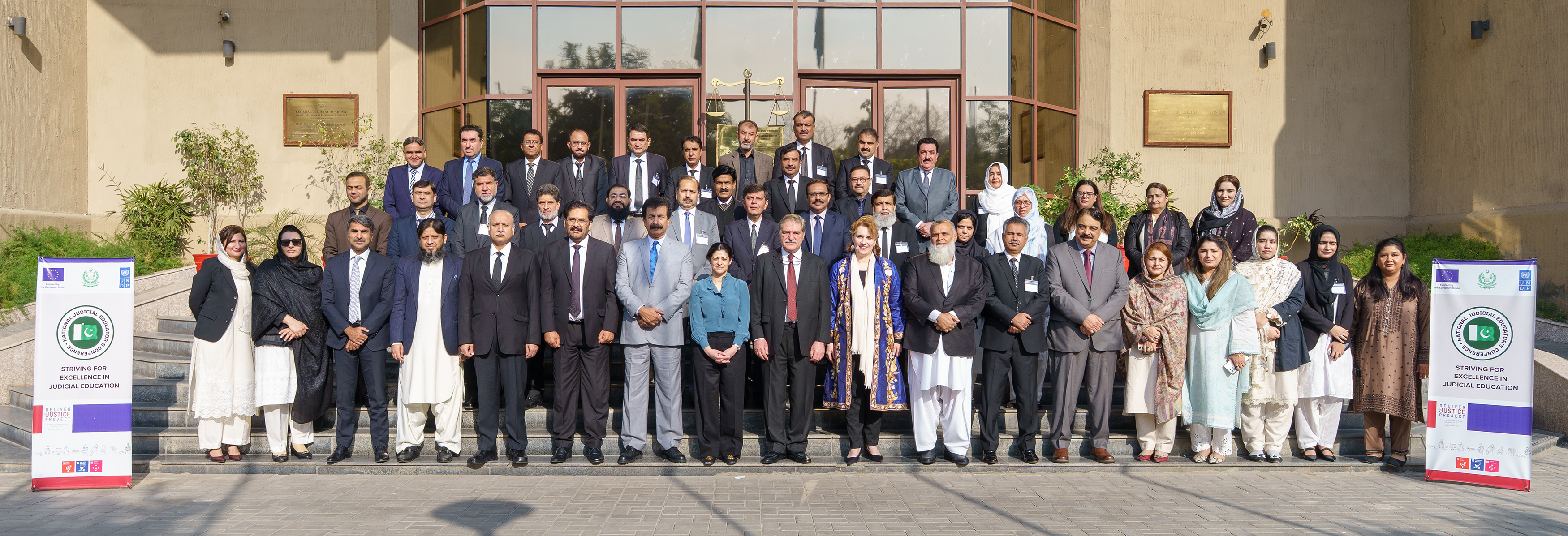 Group photo of diverse attendees standing in front of a building with banners.
