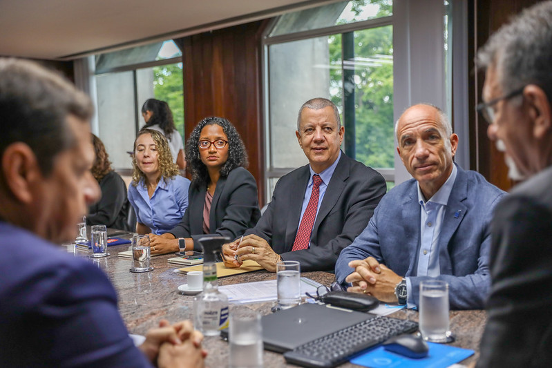 Group of professionals in a conference room around a table with laptops and beverages.
