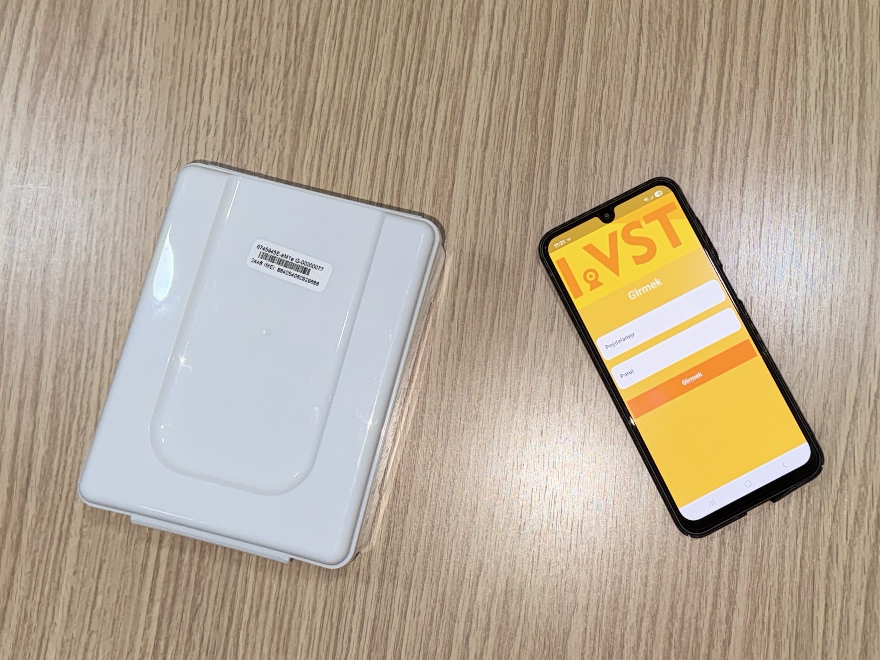 White plastic case beside a yellow striped card with 'VST' on a wooden surface.