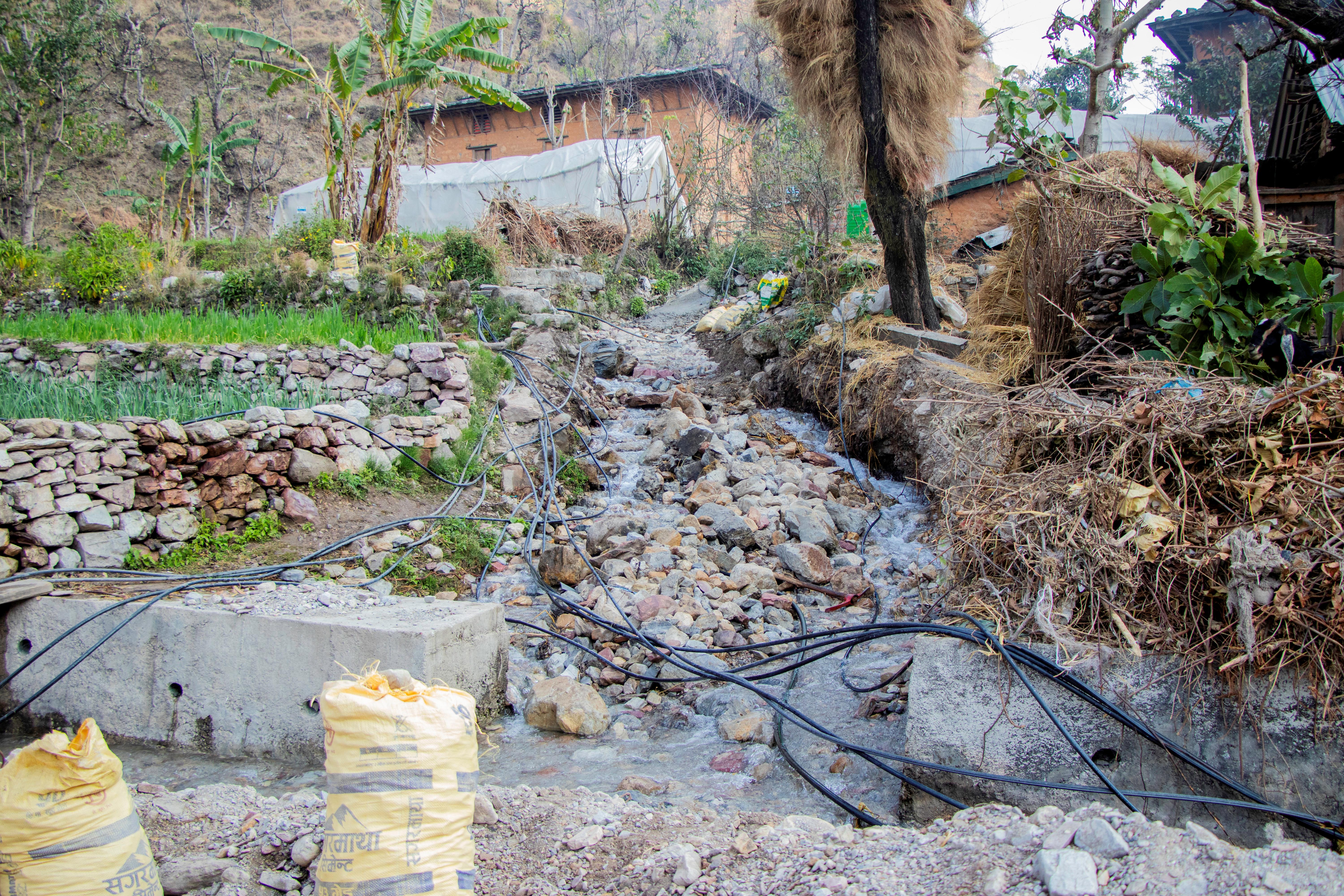 Rubble-strewn hillside with rocks, sandbags, and a damaged rural road.