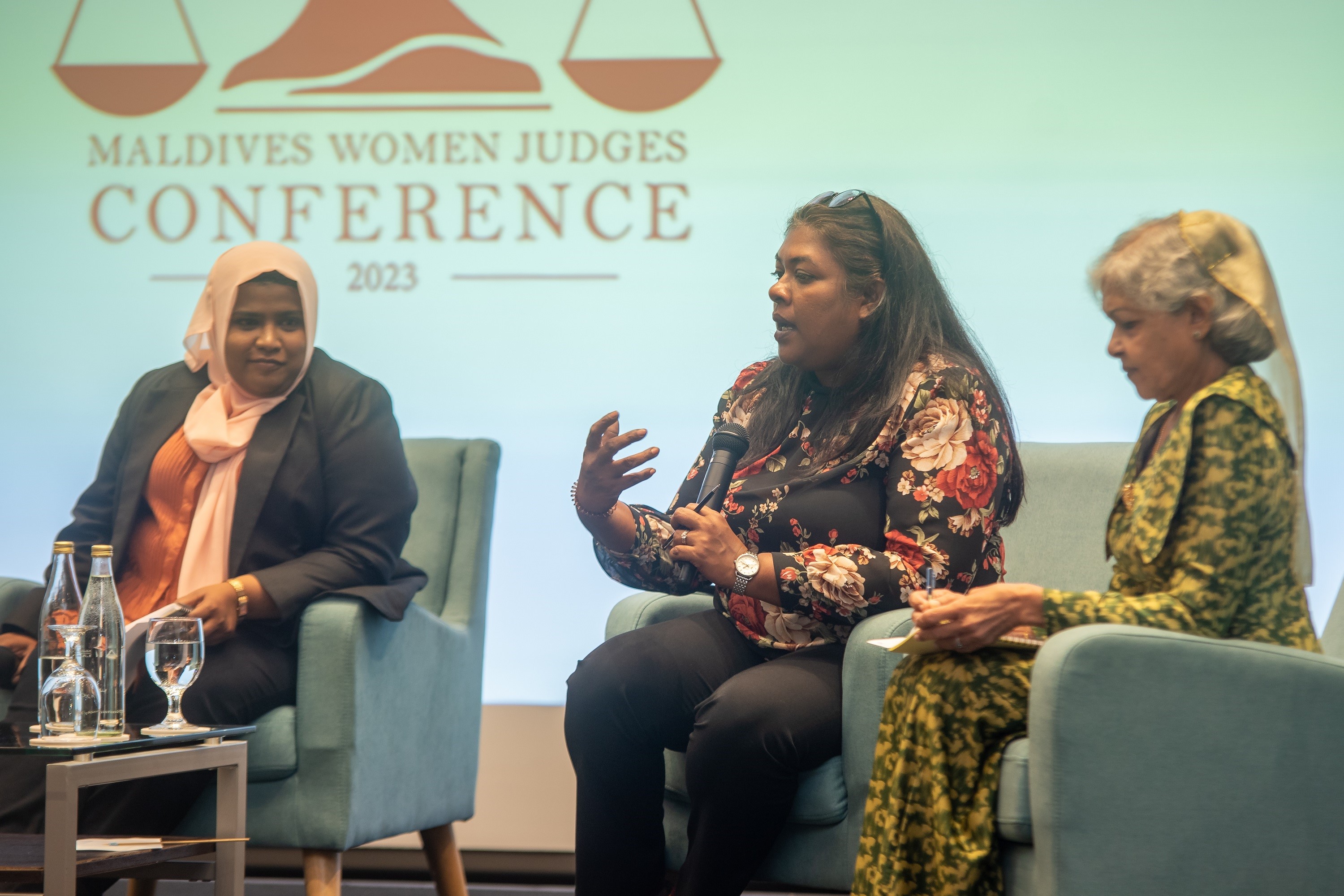 Three women panelists seated on stage at the Maldives Women Judges Conference.