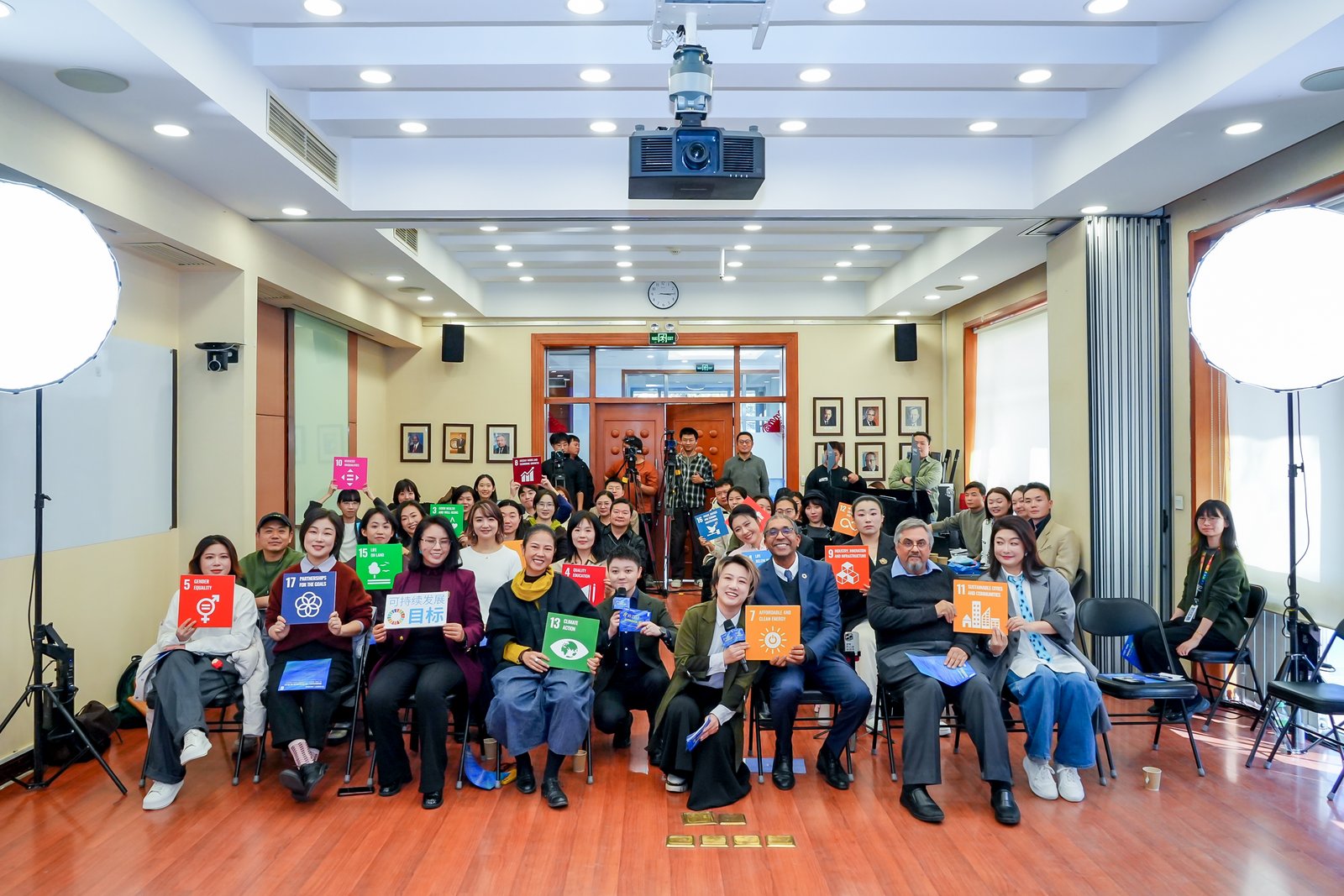 Group photo of diverse adults posing in a bright training room, many smiling.