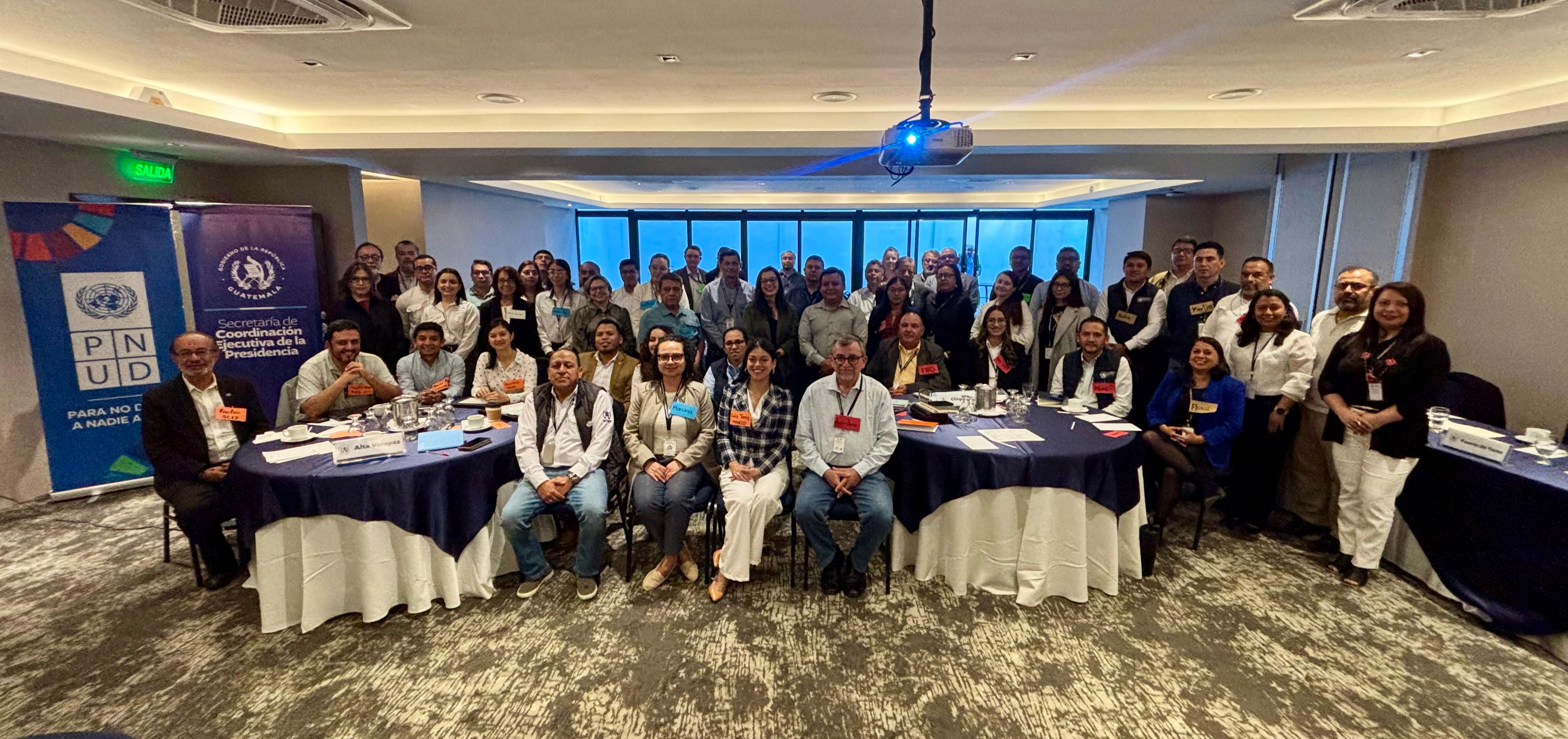 Group of professionals posing for a conference group photo in a banquet hall.