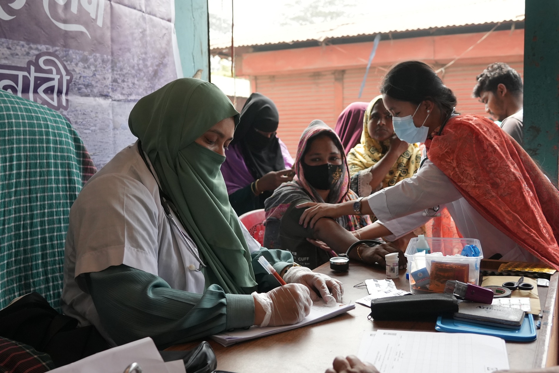 Group of volunteers outdoors at a table signing forms and assisting attendees.