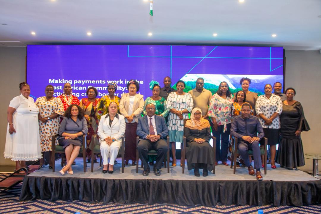 Group of diverse people on a stage with a blue backdrop, posing for a conference photo.