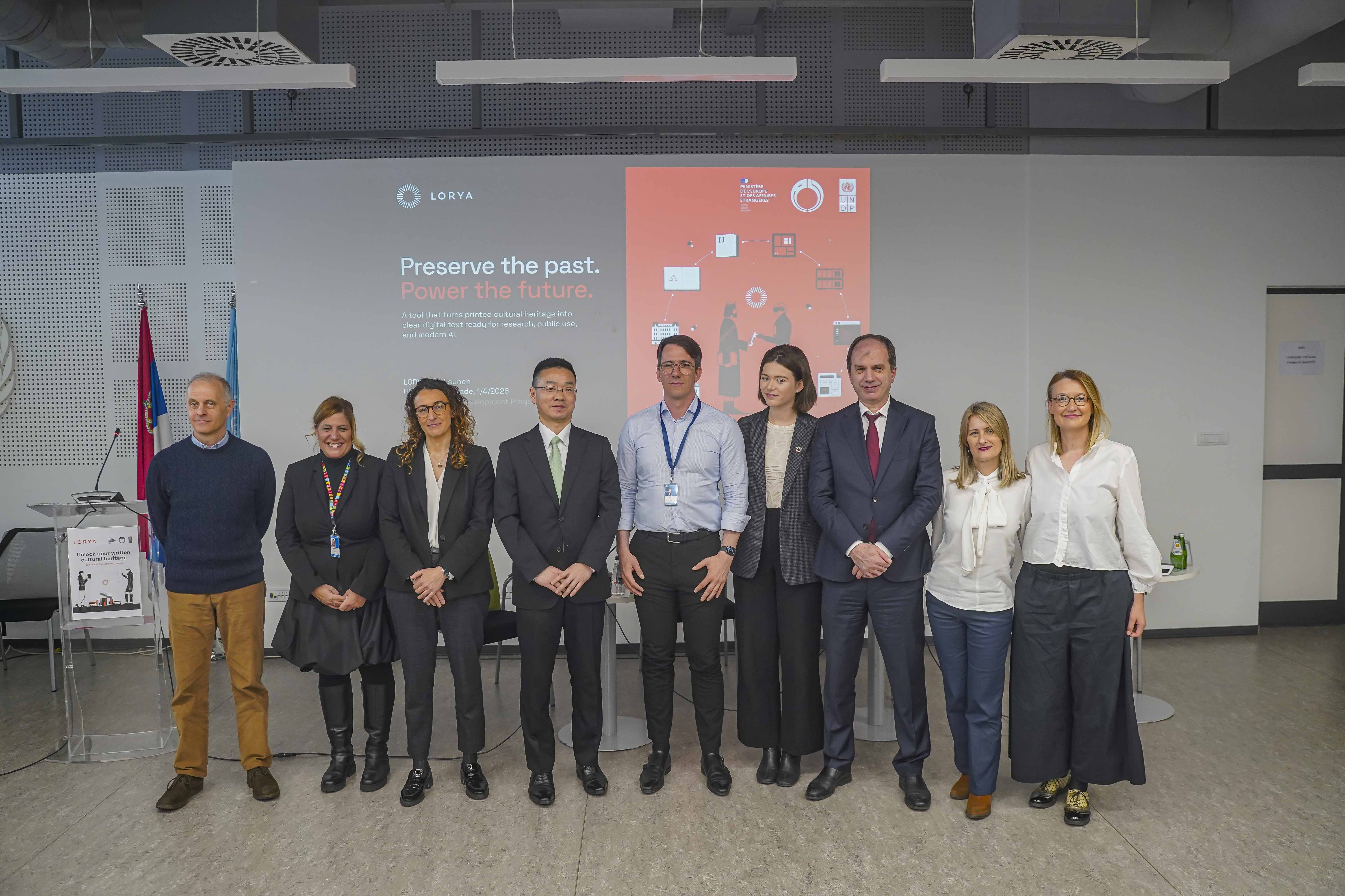 Group photo of professionals in a conference room with flags in the background.