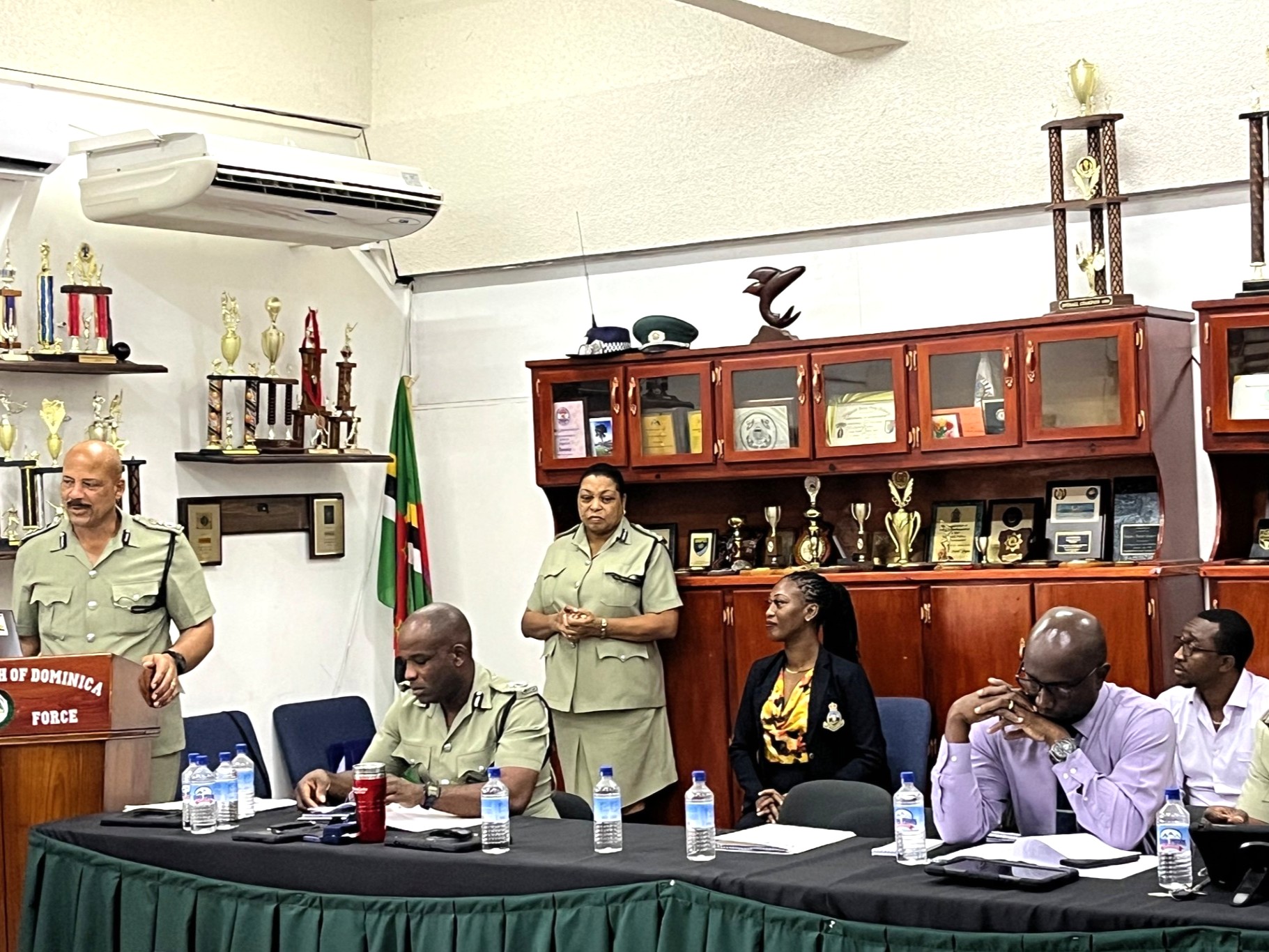 Panel of officials at a green table in a trophy-filled conference room