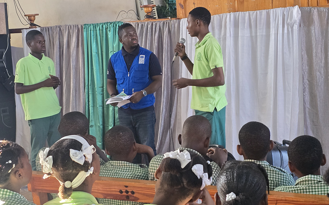 Photo: three men presenting to seated students in a classroom with colorful curtains.