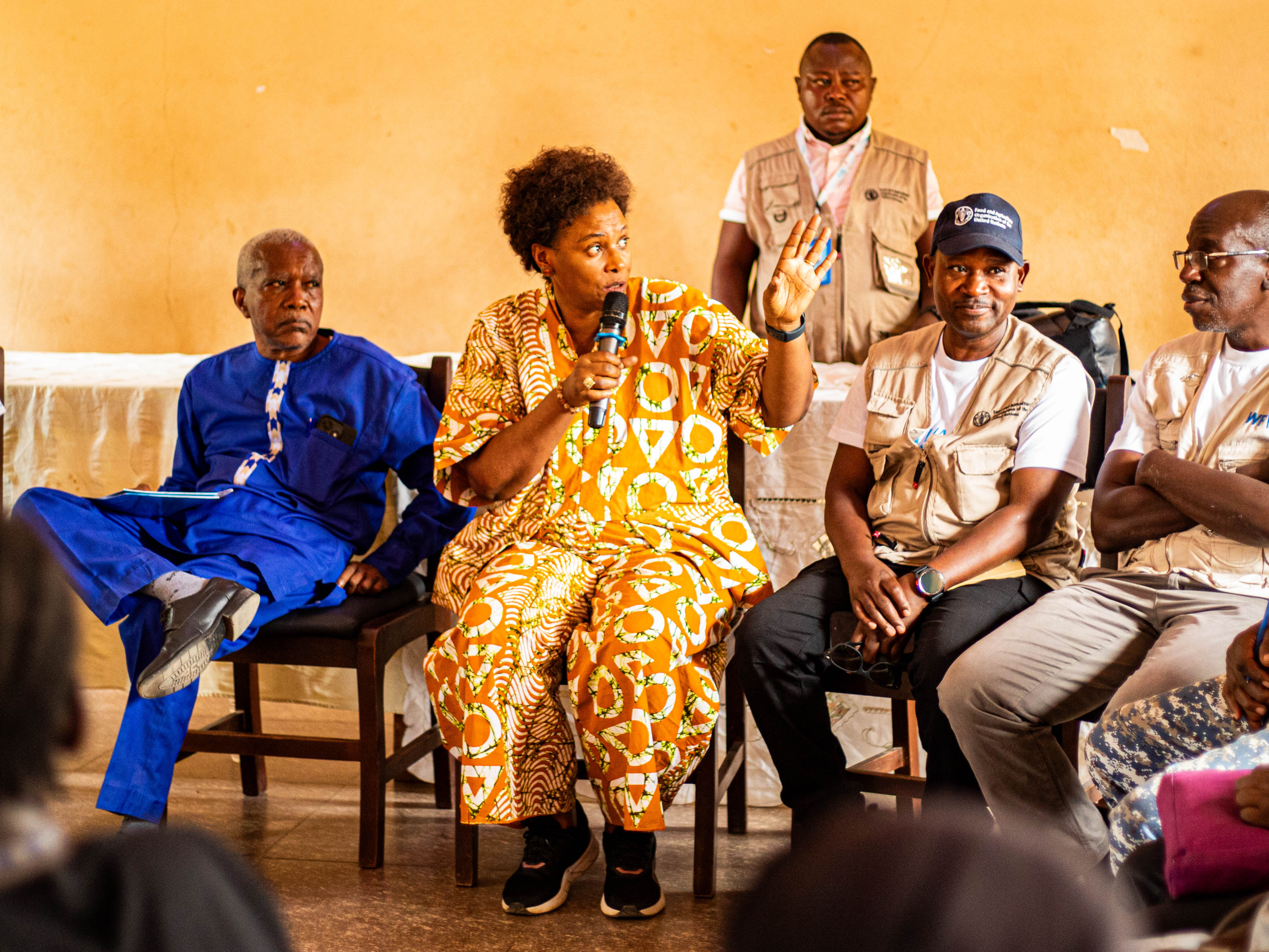 Photograph of a panel seated on a stage in bright patterned outfits.