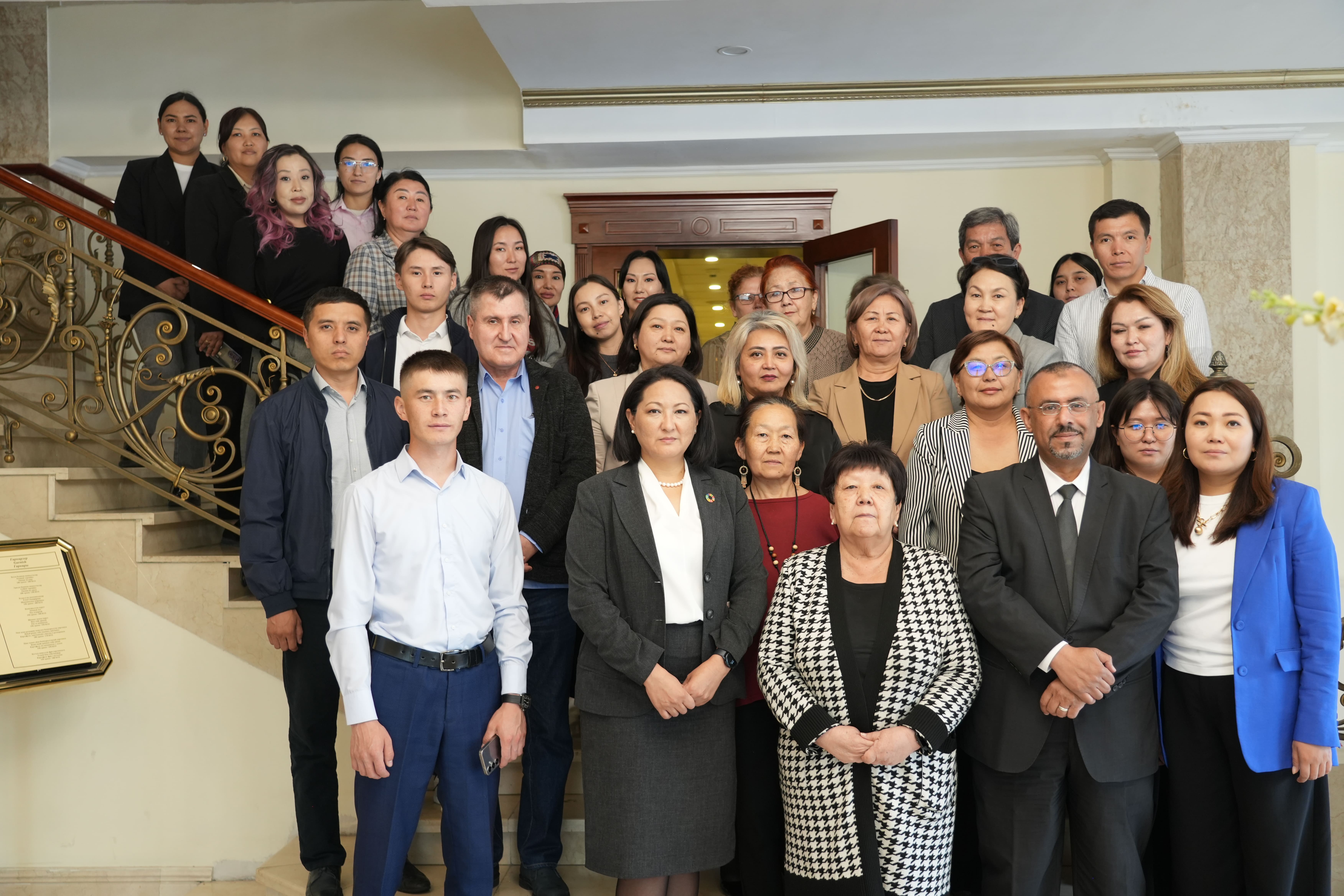 Group photo of diverse professionals in business attire posing on a staircase.