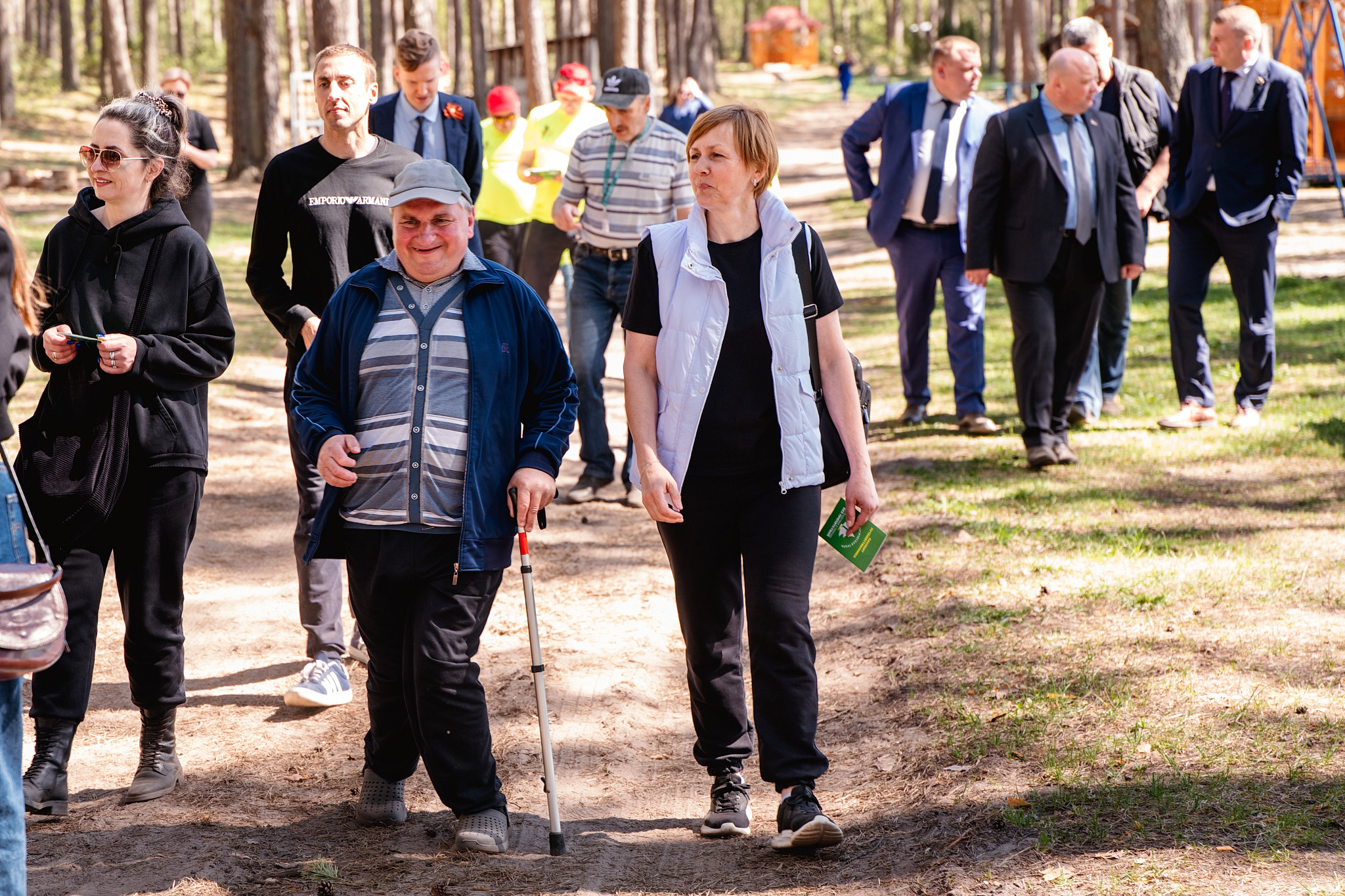 Photo: group of people walking in a sunny park, some with canes.