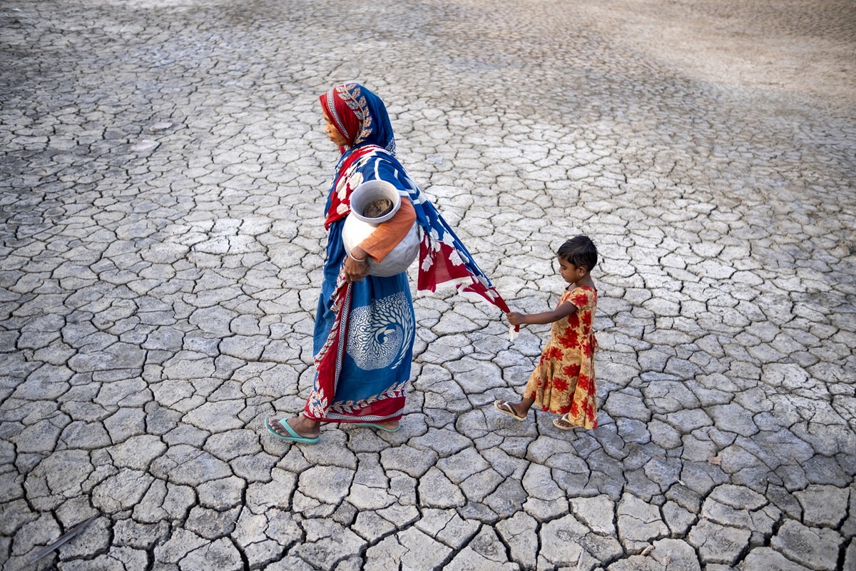 A woman in coastal area in Bangladesh fetching water while her child follows her