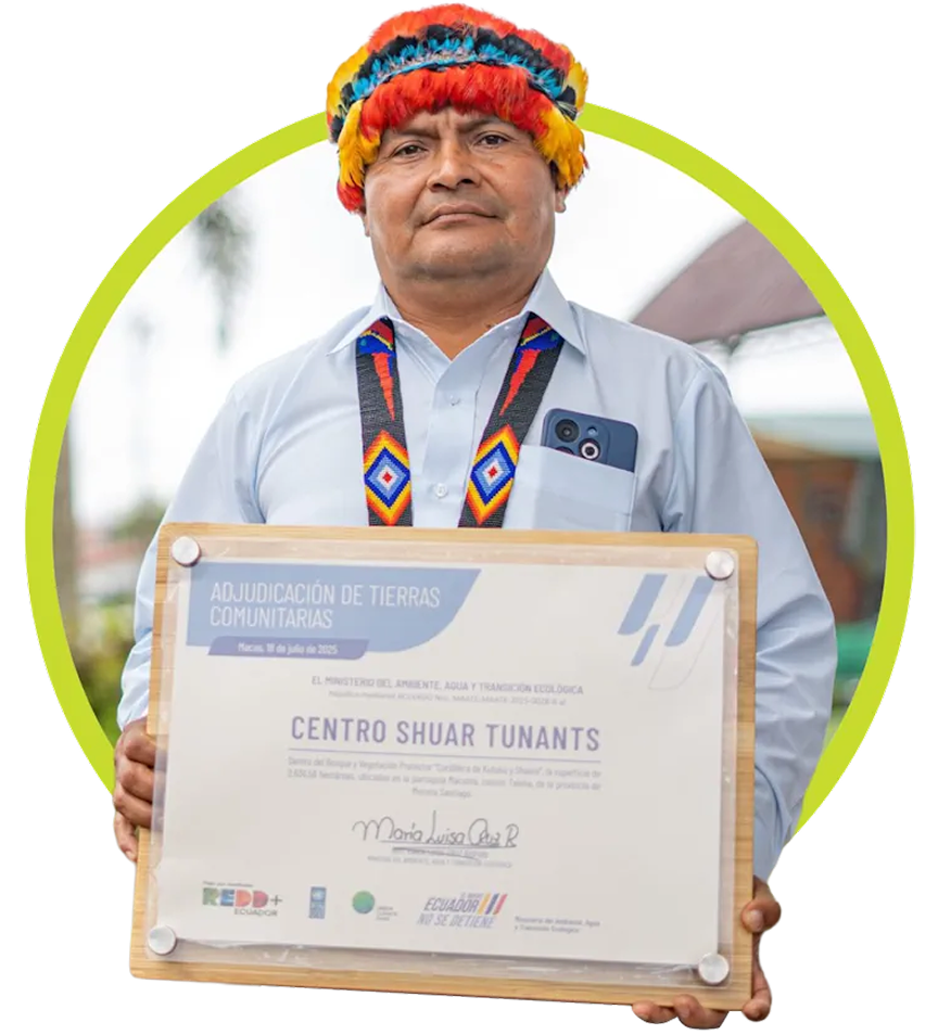 A man wearing a traditional feathered headdress holds up a certificate 