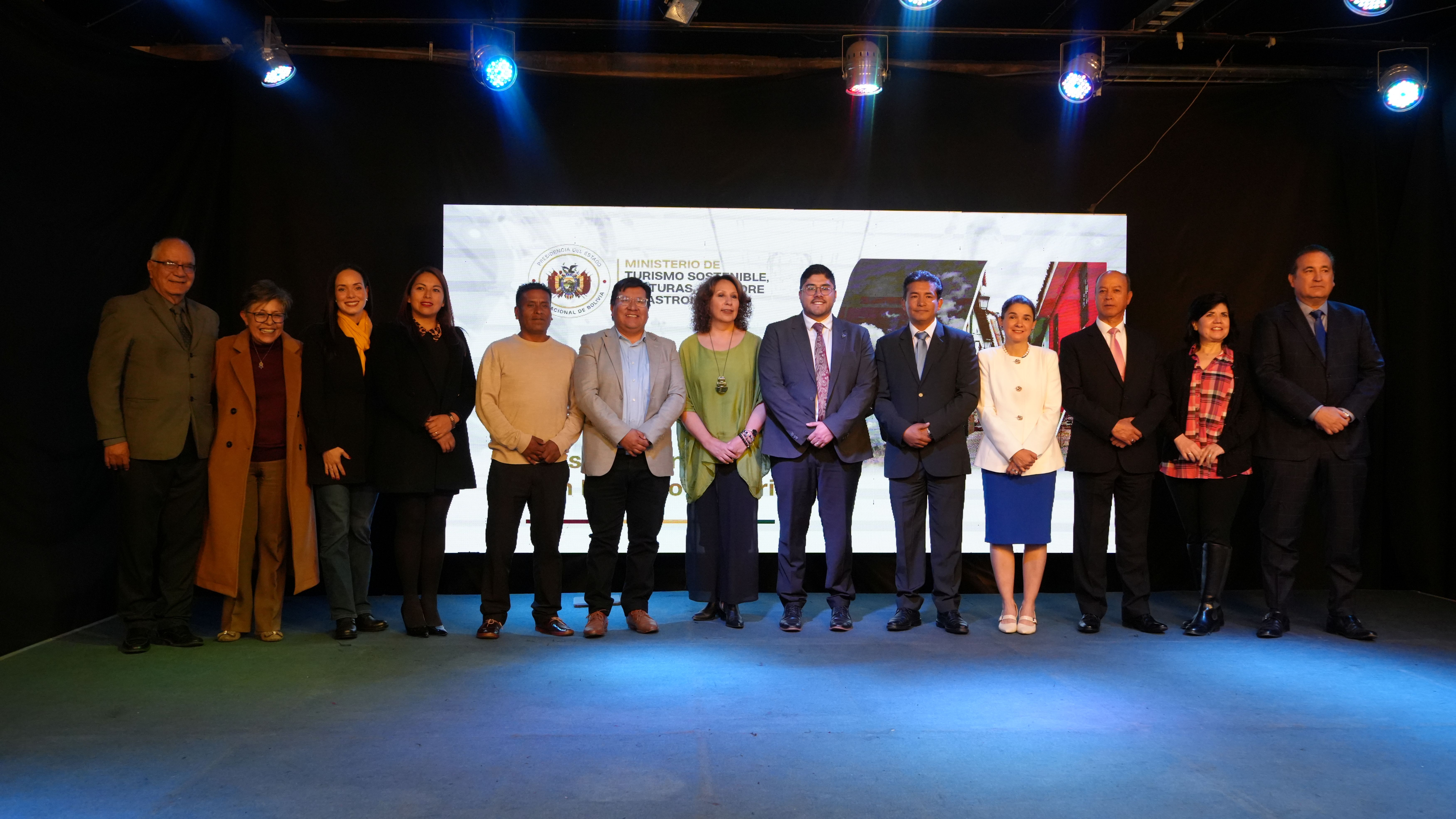 Group photo on stage under blue lights with a logo screen behind.
