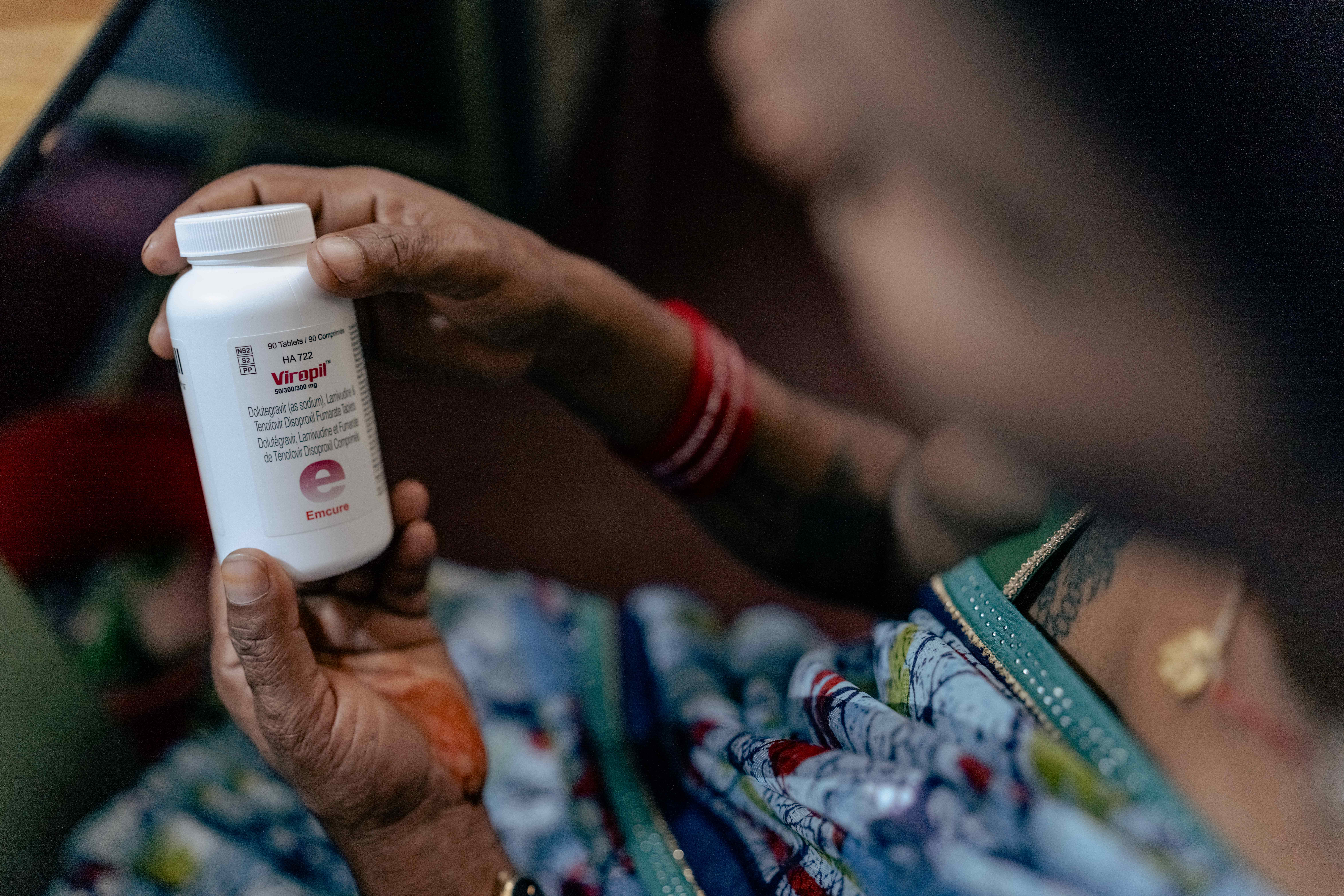 Close-up of hands holding a white medicine bottle outdoors.