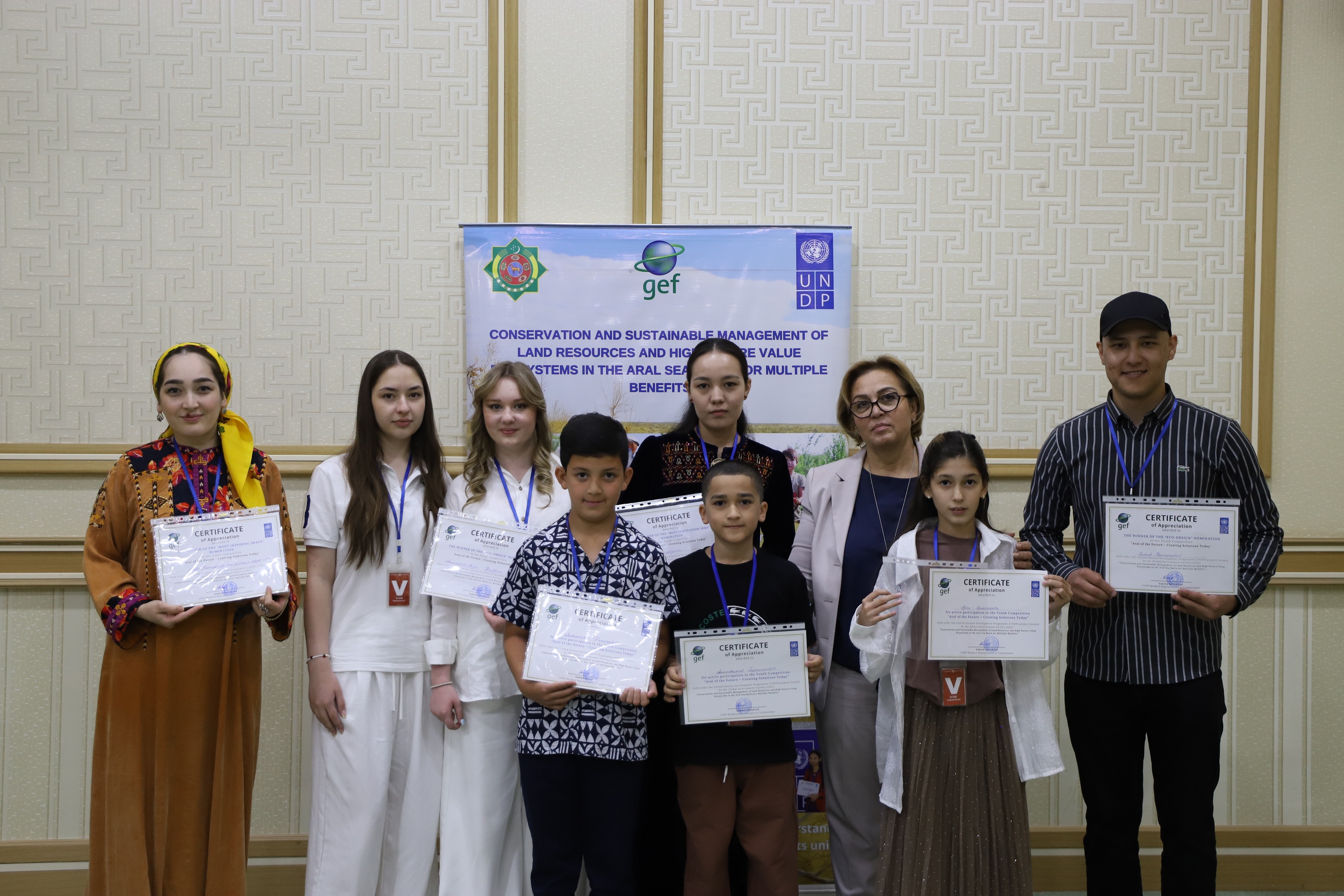 Group of students and instructors posing with certificates in front of a banner.