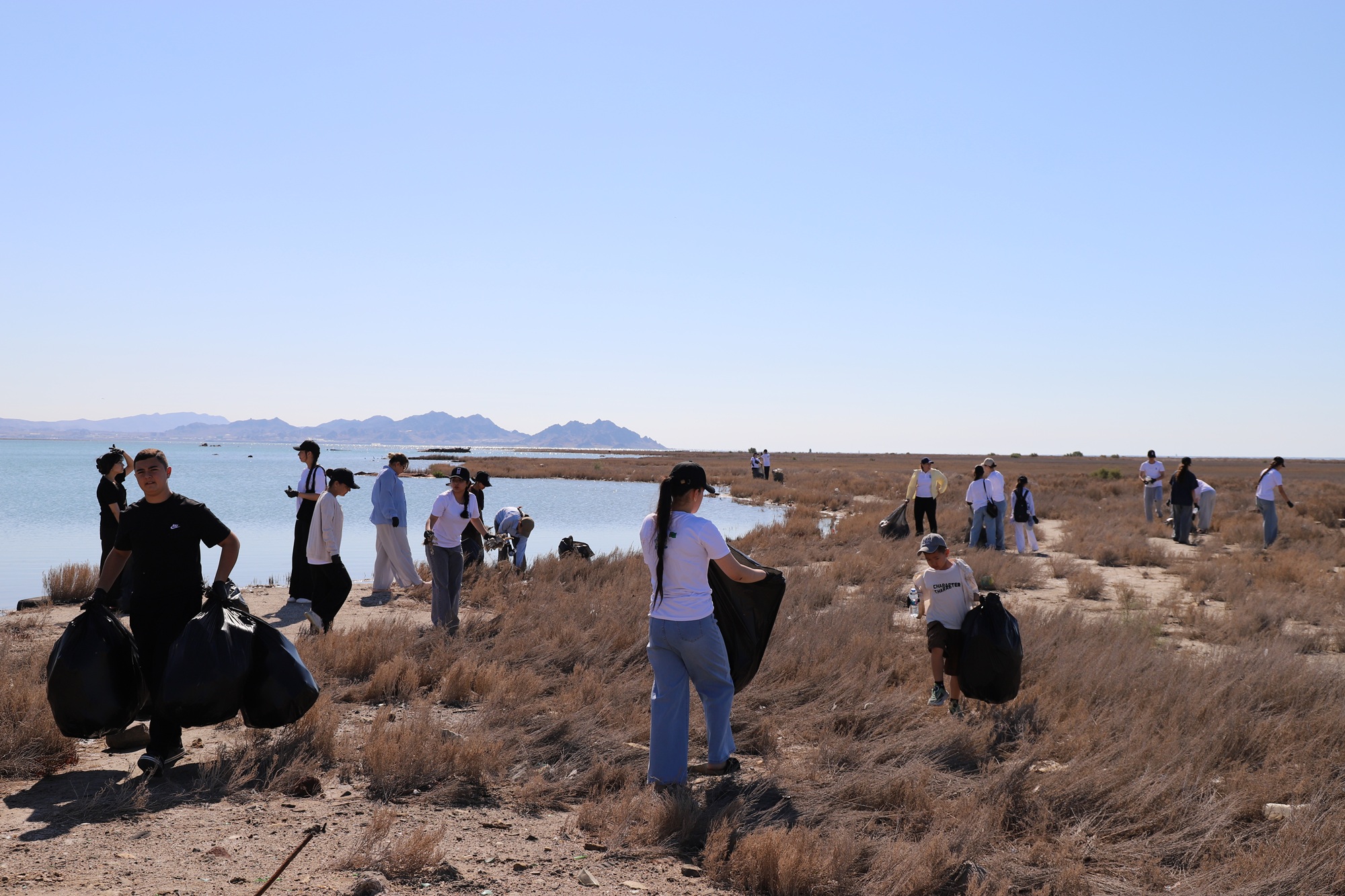 Photograph of a film crew filming in a dry desert landscape with distant mountains.