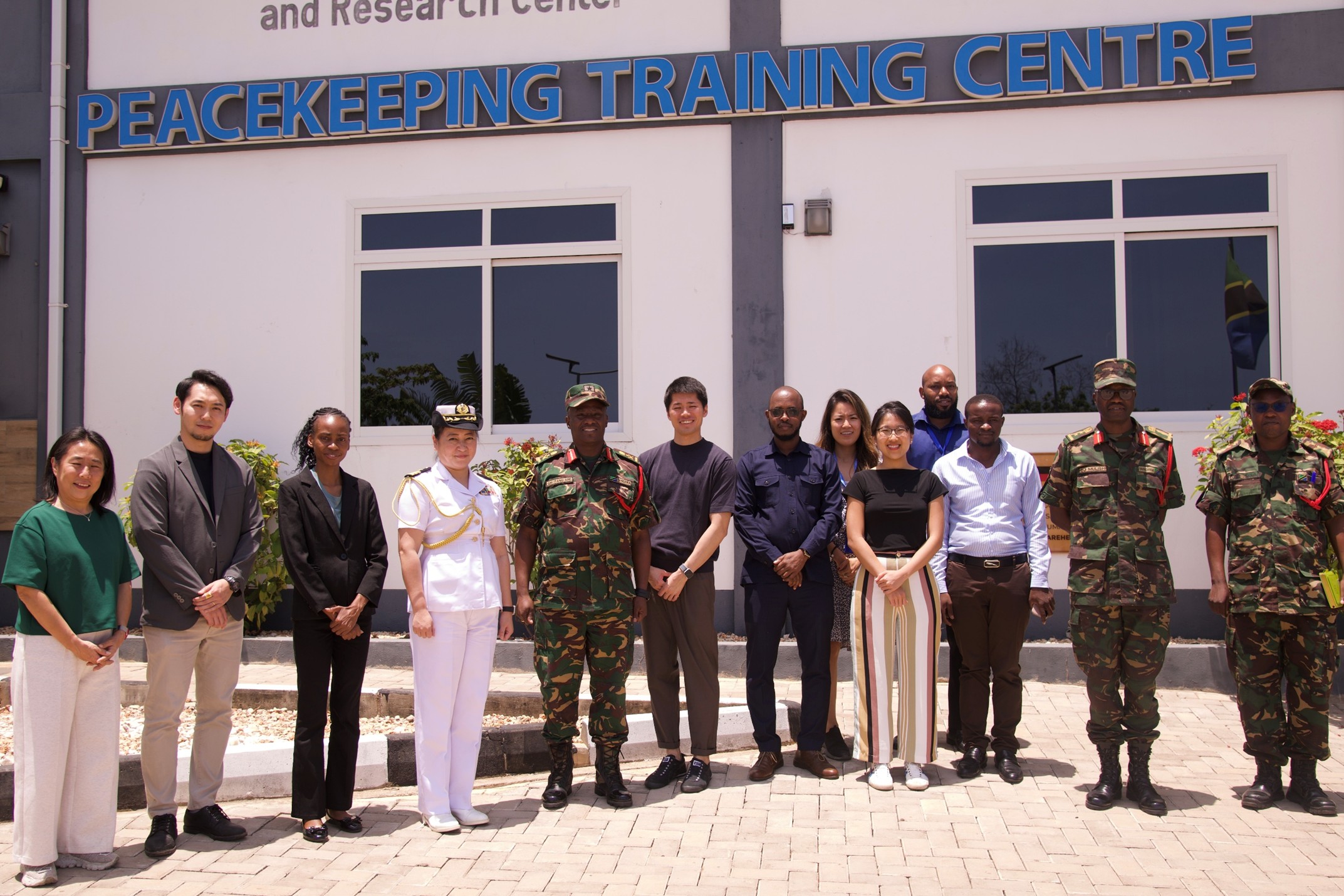 Group of people in front of Peacekeeping Training Centre; mix of military and civilian clothing.