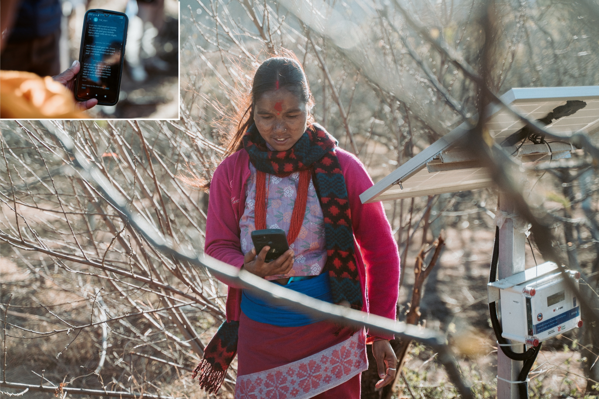 Woman in a pink sweater outdoors in winter, holding a blue clipboard near a sensor on a post.