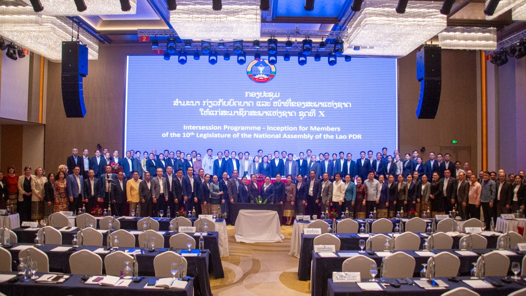 Photograph: group on stage at a formal conference in a large auditorium.
