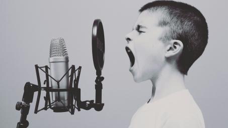Black and white shot of young kid hollering into a microphone